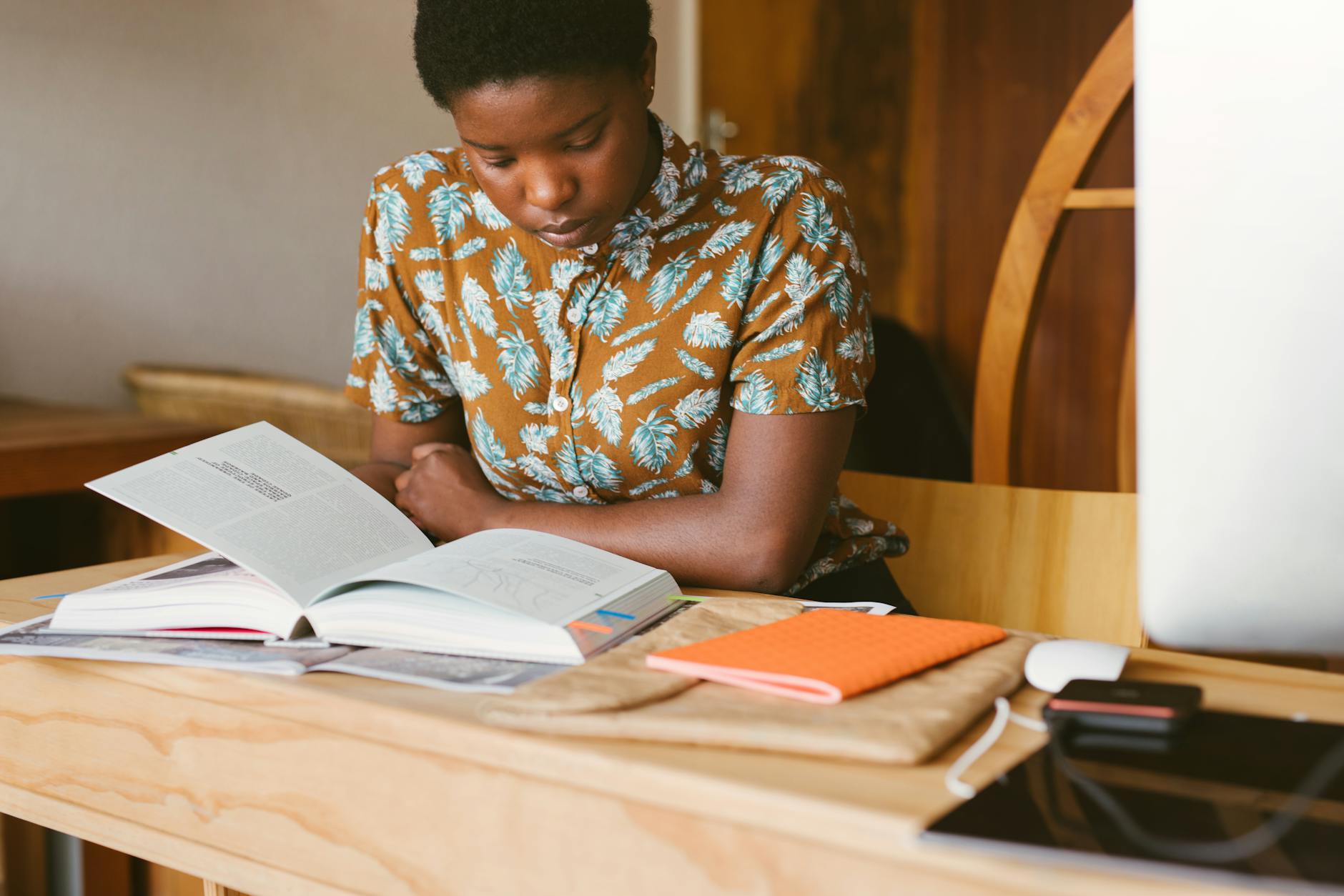 A young woman studies a book at her desk in a warm, indoor setting, illustrating a calm study environment — TransferCredit.org