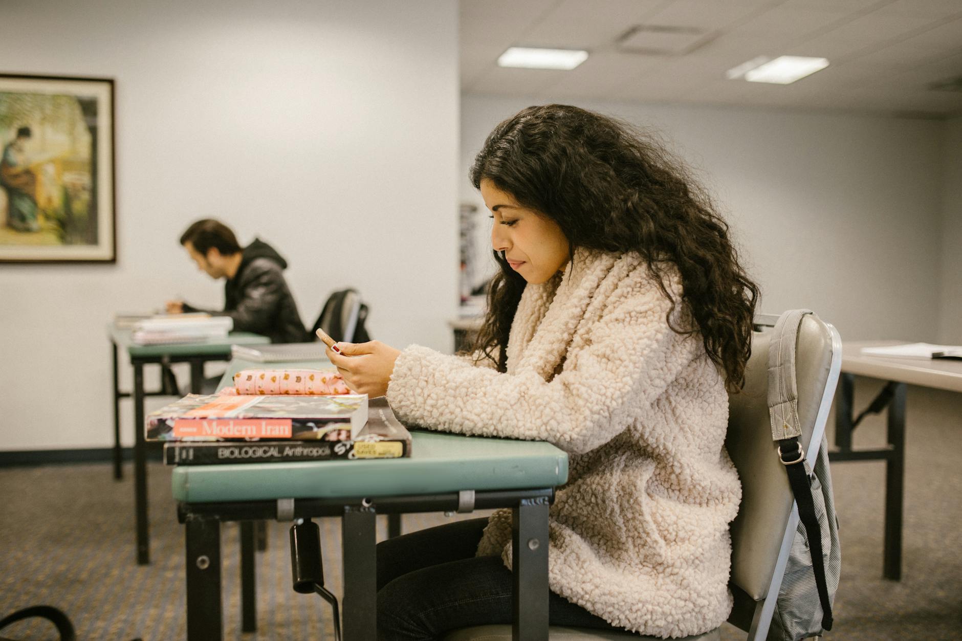 Female college student focusing on study materials in a classroom setting — TransferCredit.org