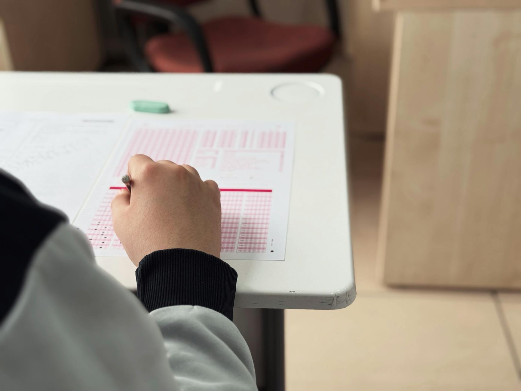 Close-up of student answering a test in a classroom environment — TransferCredit.org