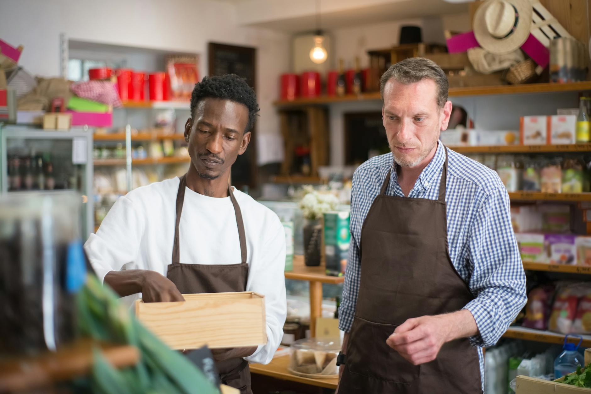 Two male employees organizing products in a cozy grocery store — TransferCredit.org