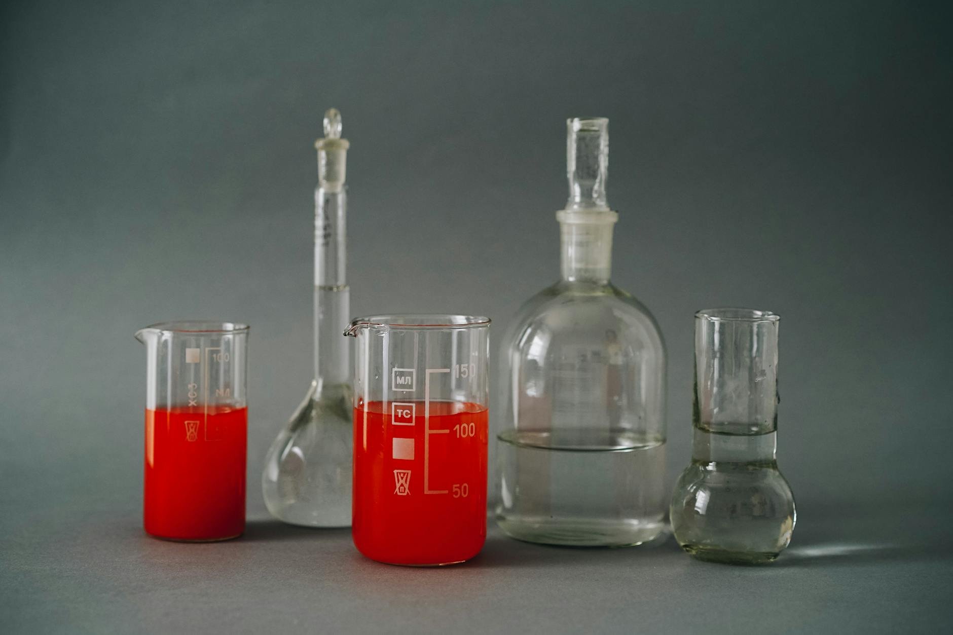 Close-up of laboratory glassware with colorful red liquids used in a chemistry lab — TransferCredit.org