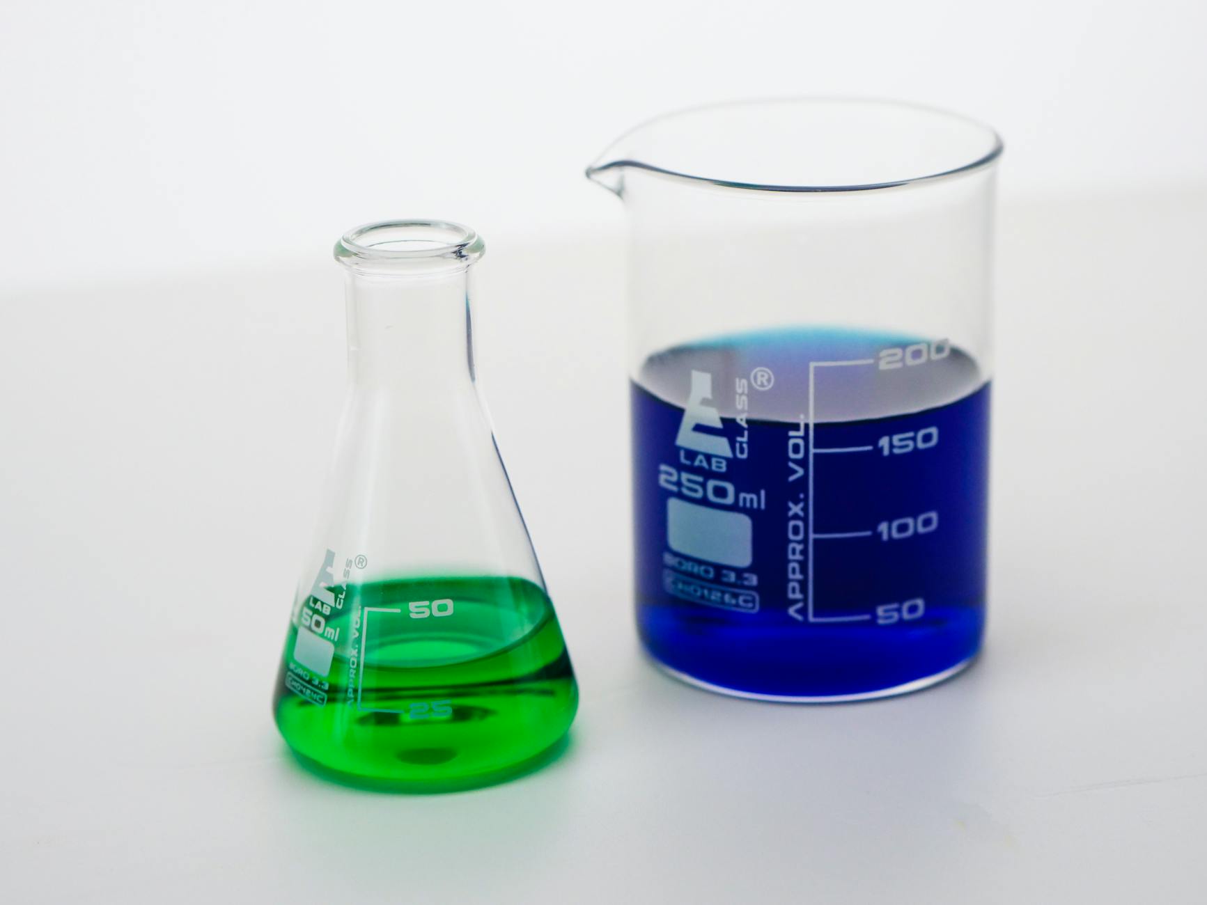 Close-up of beakers filled with vibrant green and blue liquids in a laboratory setting — TransferCredit.org