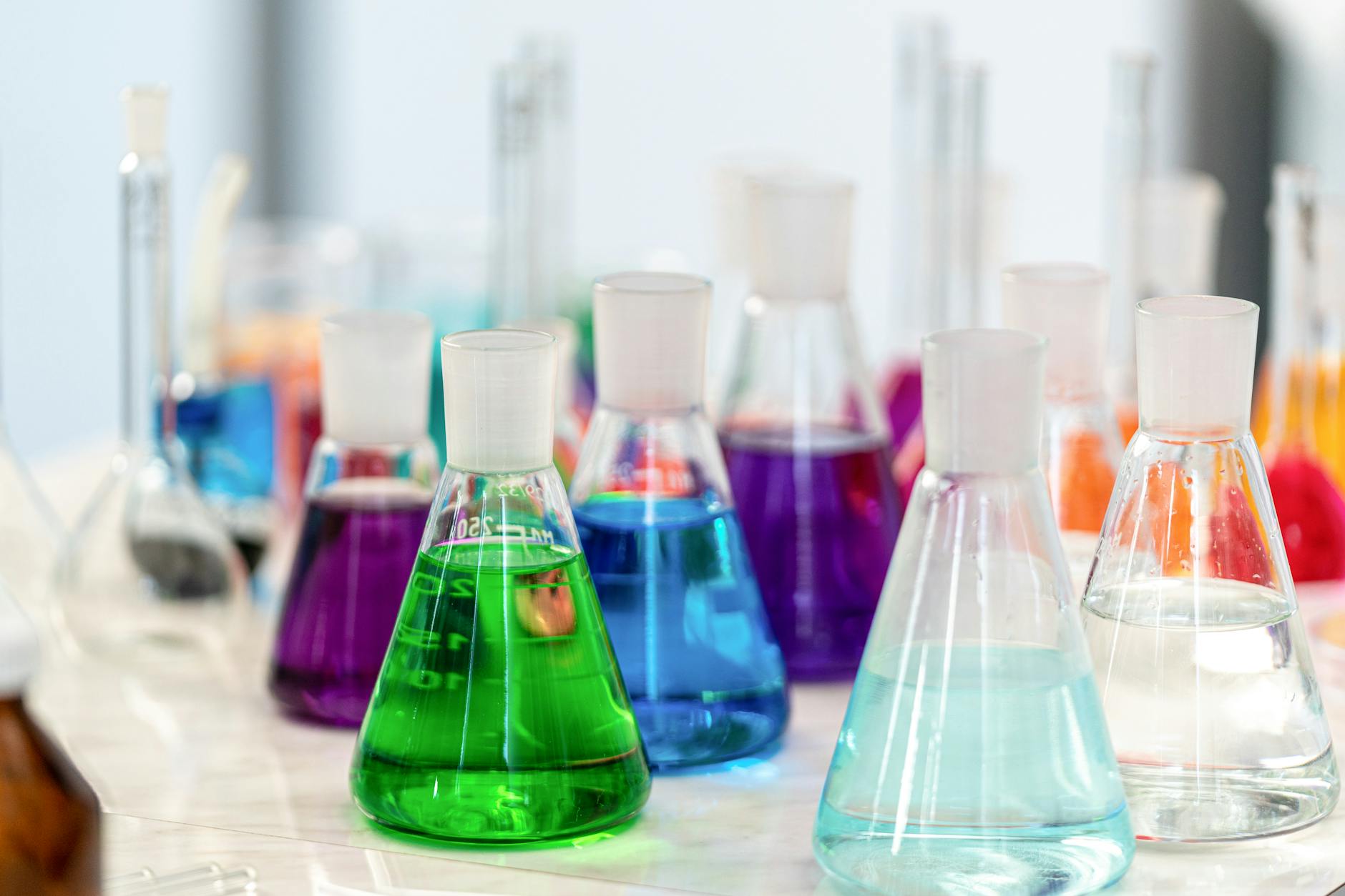 Close-up of colorful chemical solutions in glass beakers in a laboratory setting — TransferCredit.org