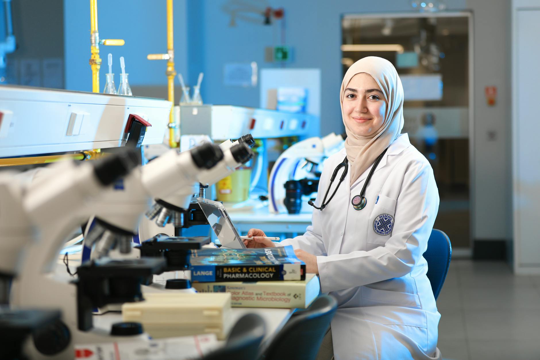 A female scientist in a laboratory setting, conducting research with microscopes and reference books — TransferCredit.org