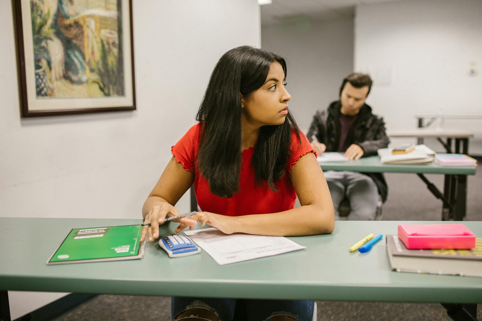 Students taking a test in a classroom, with one woman looking sideways. Education theme — TransferCredit.org