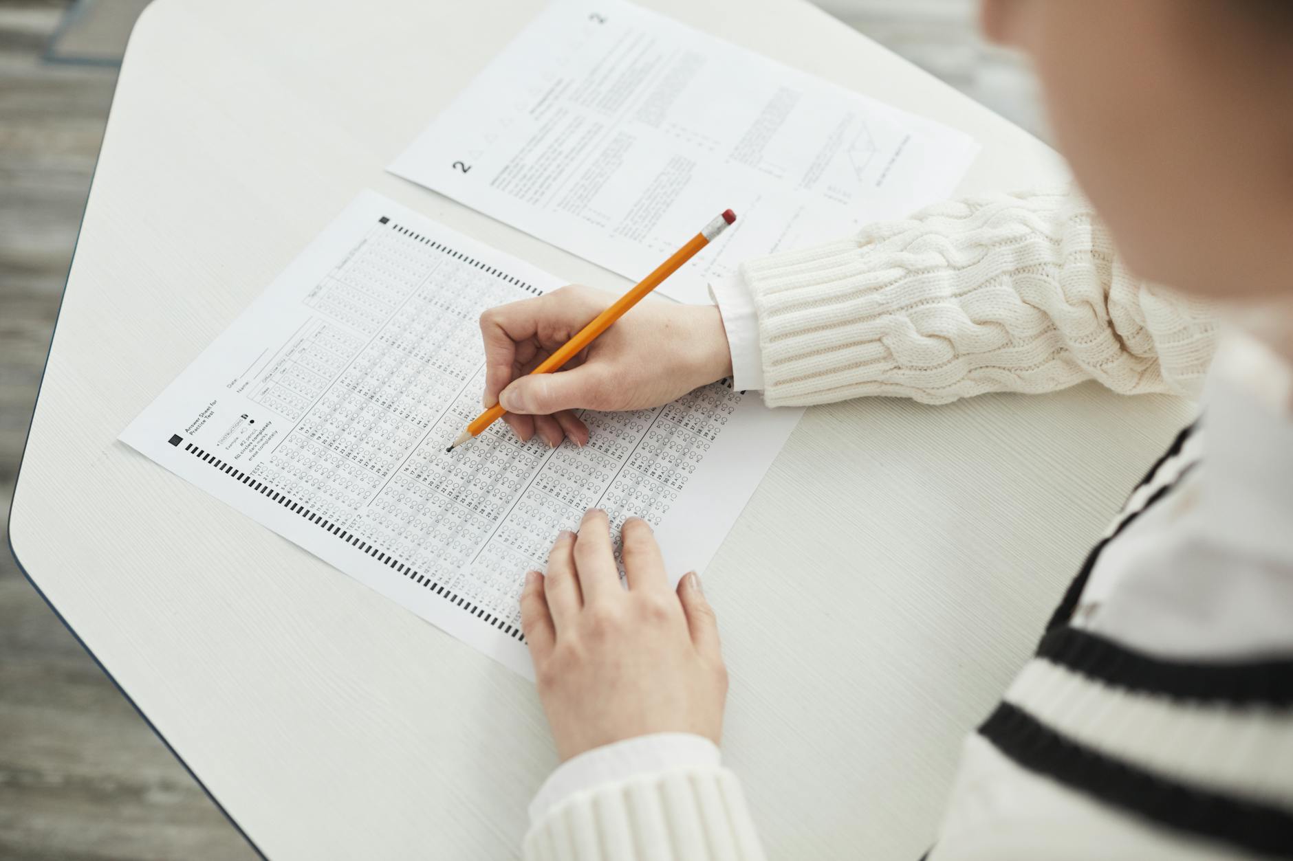 Close-up of a student filling out a multiple-choice exam in a quiet classroom setting — TransferCredit.org