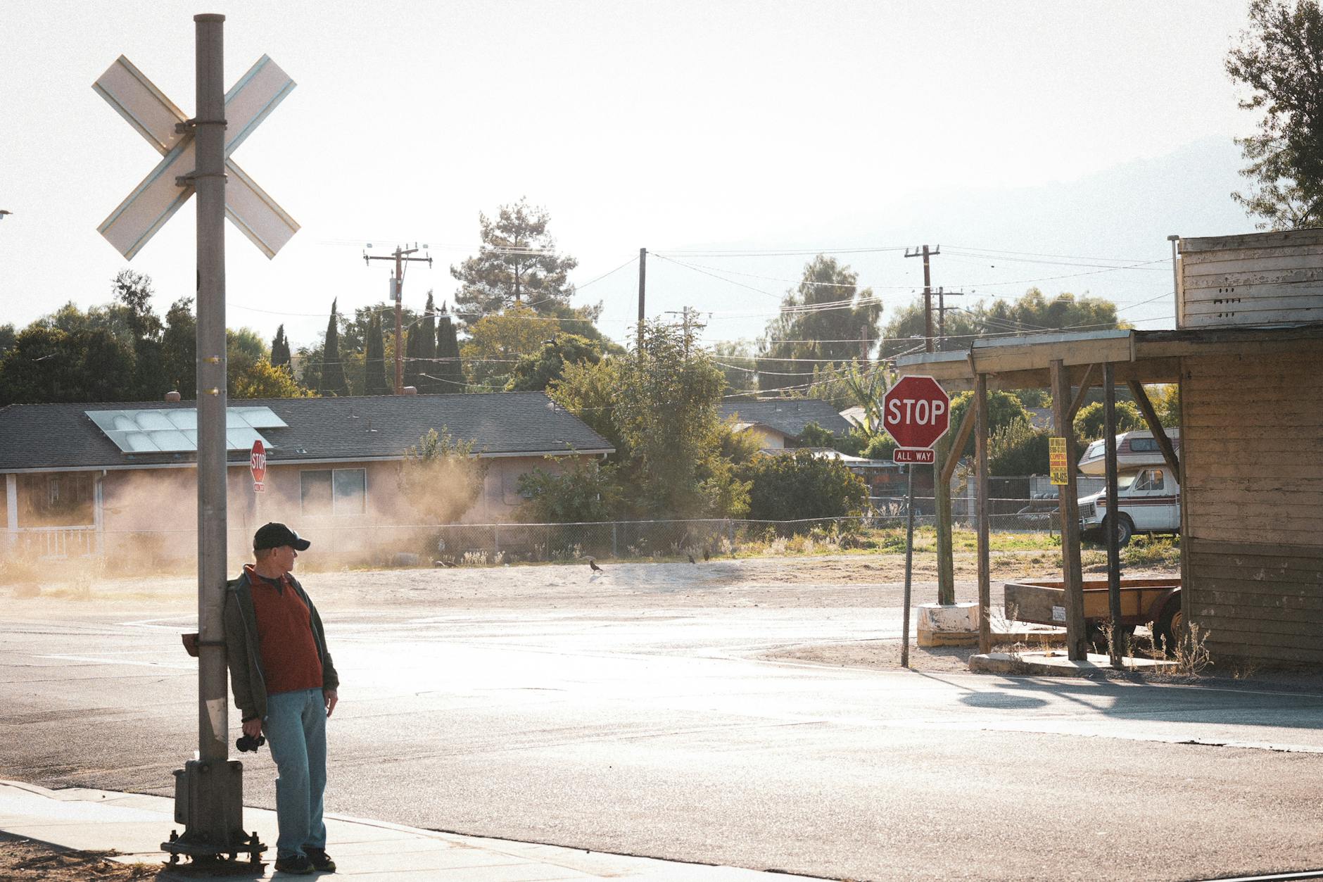 Casual scene of a man leaning on a signpost under bright daylight on a city street corner — TransferCredit.org