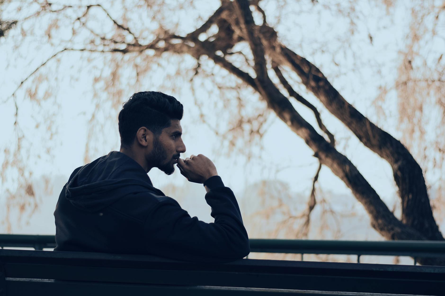 Man in deep thought sitting on a bench in a serene autumn park setting — TransferCredit.org