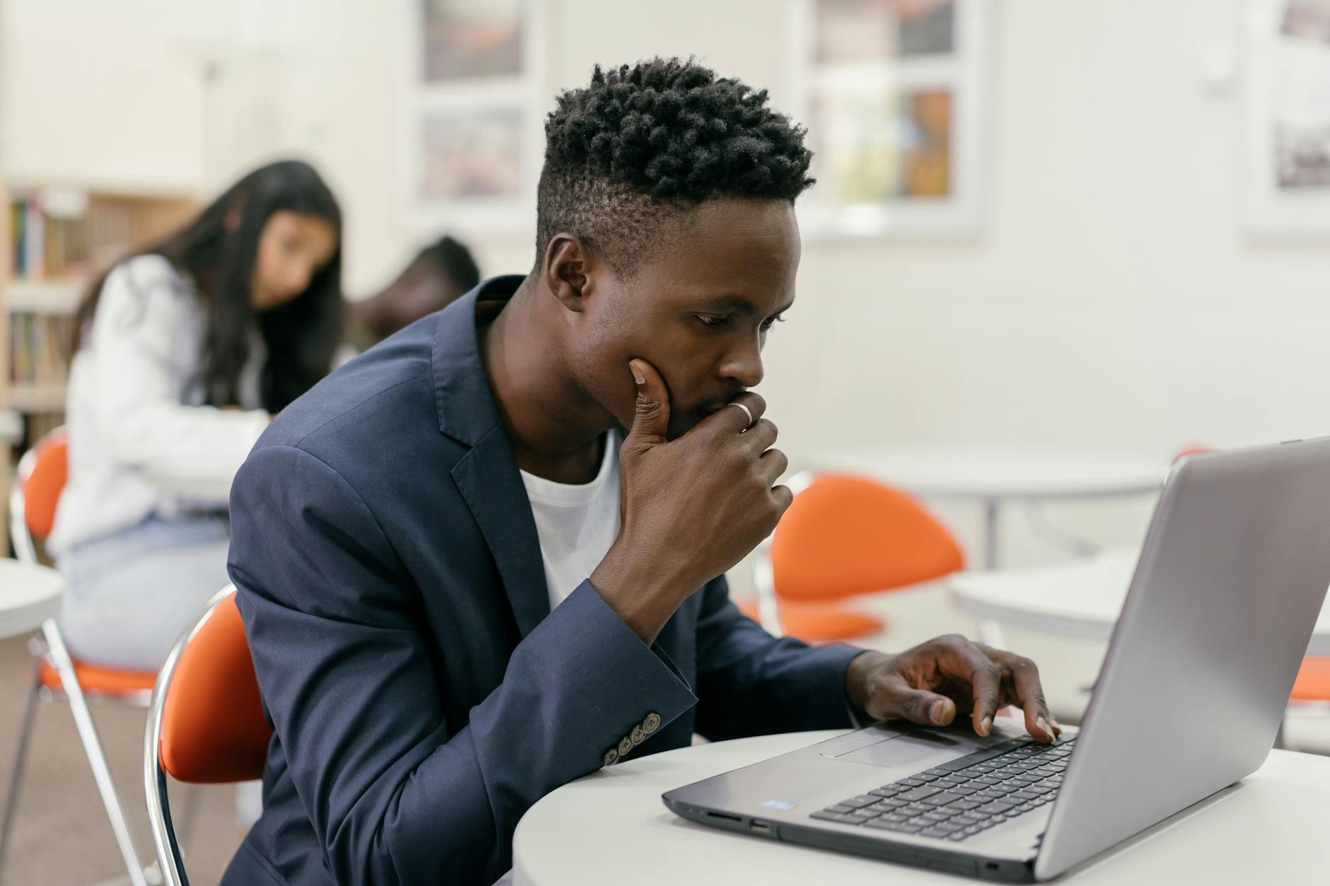 Focused student sitting at a laptop in a modern classroom setting — TransferCredit.org