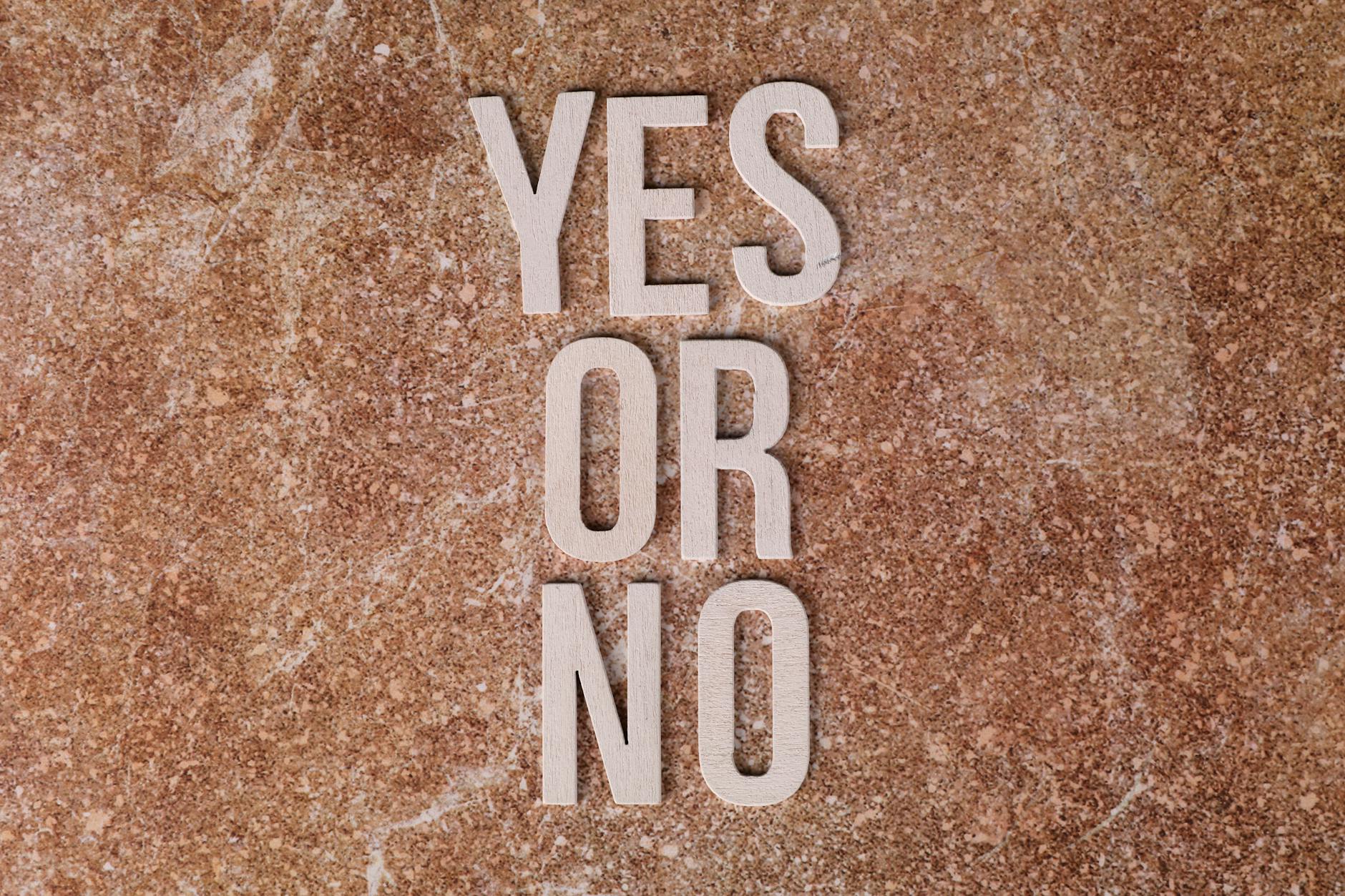 Wooden letters on marble background spell 'YES OR NO' symbolizing choices — TransferCredit.org