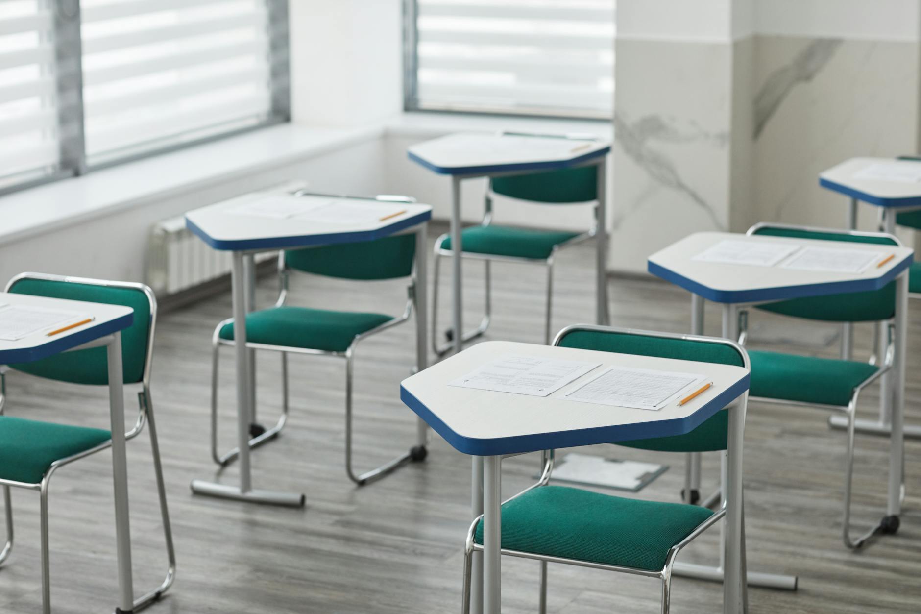 An empty classroom with arranged desks, exam papers, and pencils ready for students — TransferCredit.org