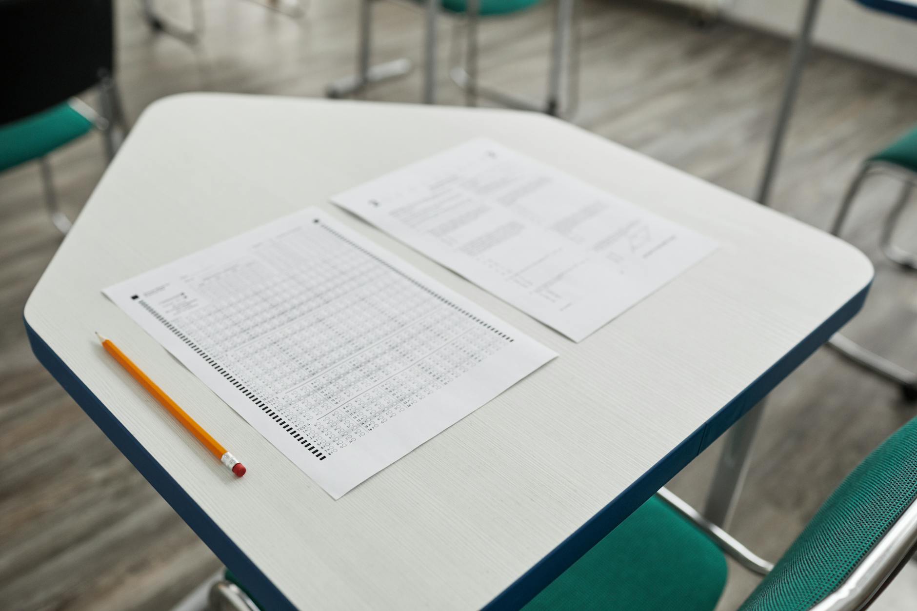 A close-up image of an exam paper and pencil on a classroom desk, ready for a test — TransferCredit.org