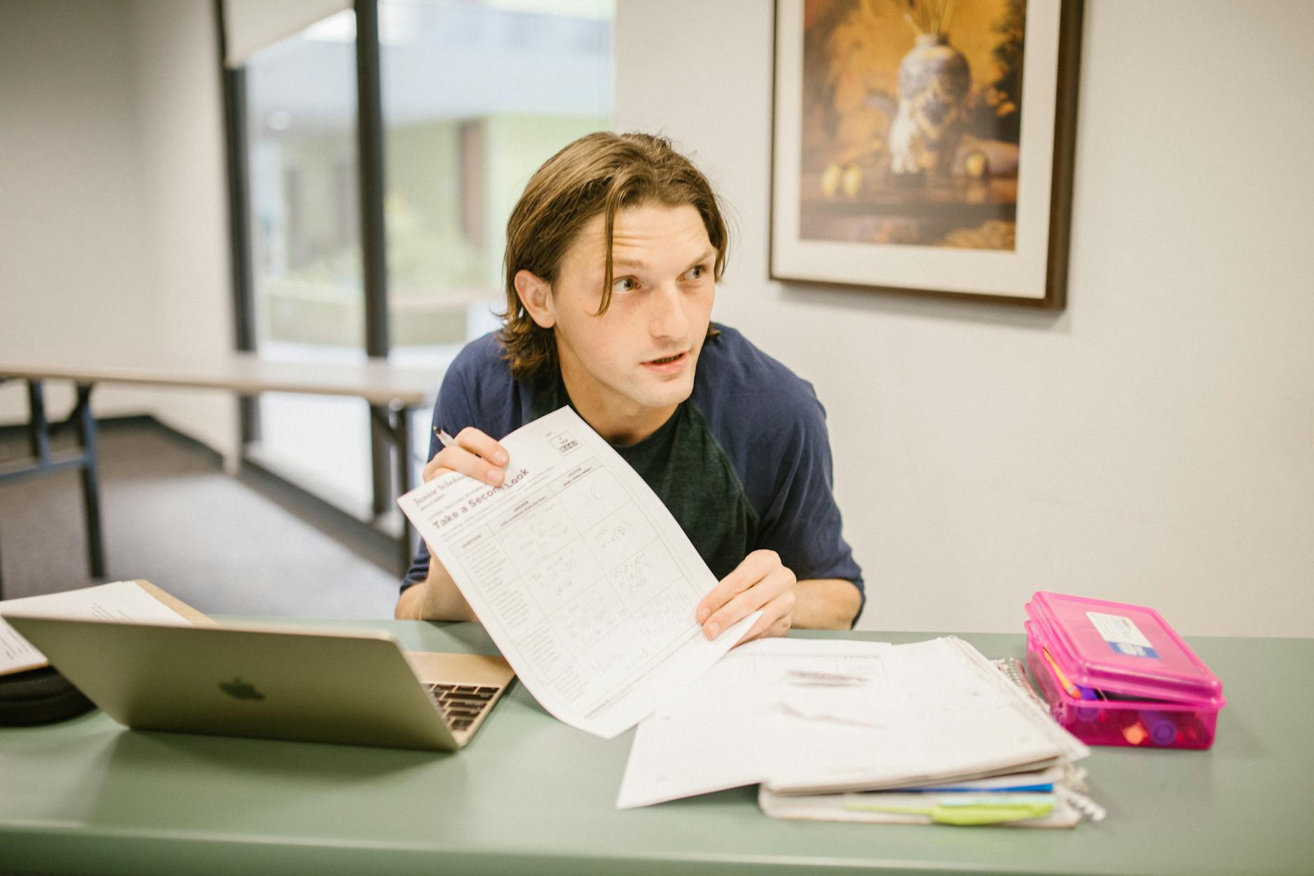 A student reviews notes on a desk with a laptop, preparing for an important exam — TransferCredit.org