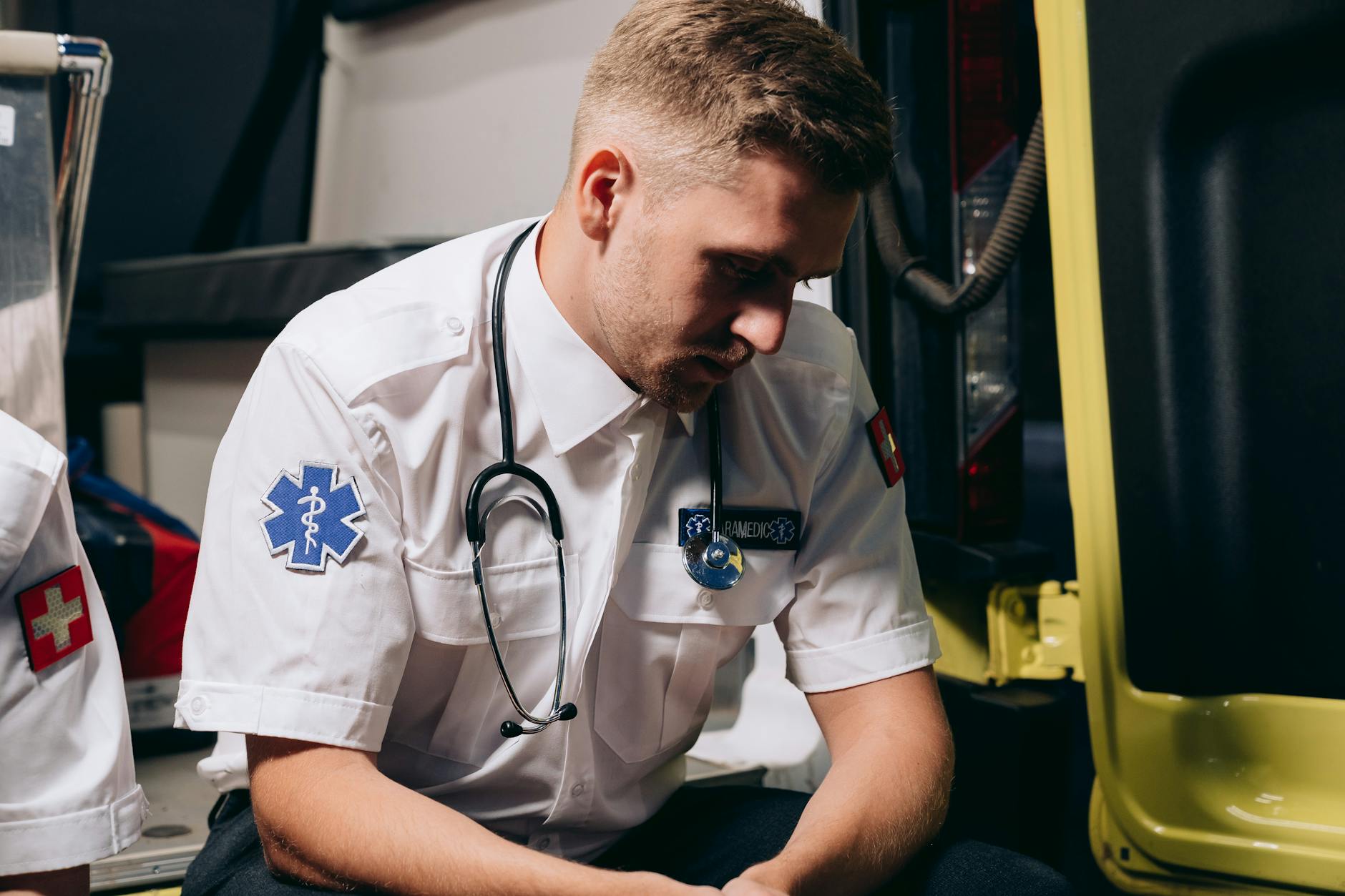 A paramedic in uniform sits pensively inside an ambulance, conveying healthcare dedication — TransferCredit.org