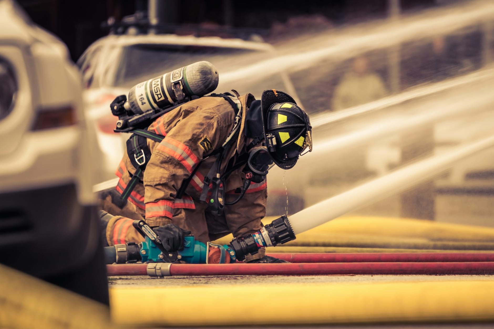 Firefighter in full gear handling water hose during emergency response training outdoors — TransferCredit.org