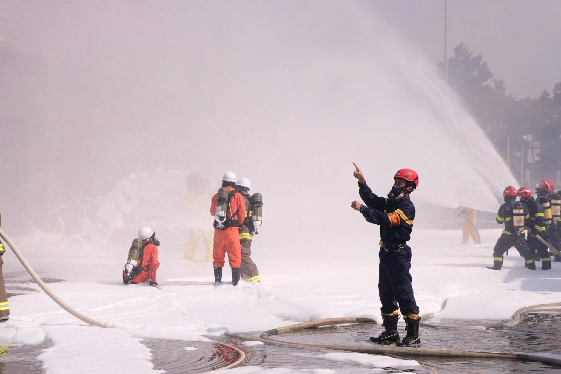 Firefighters in protective gear conduct a foam spraying training exercise outdoors — TransferCredit.org
