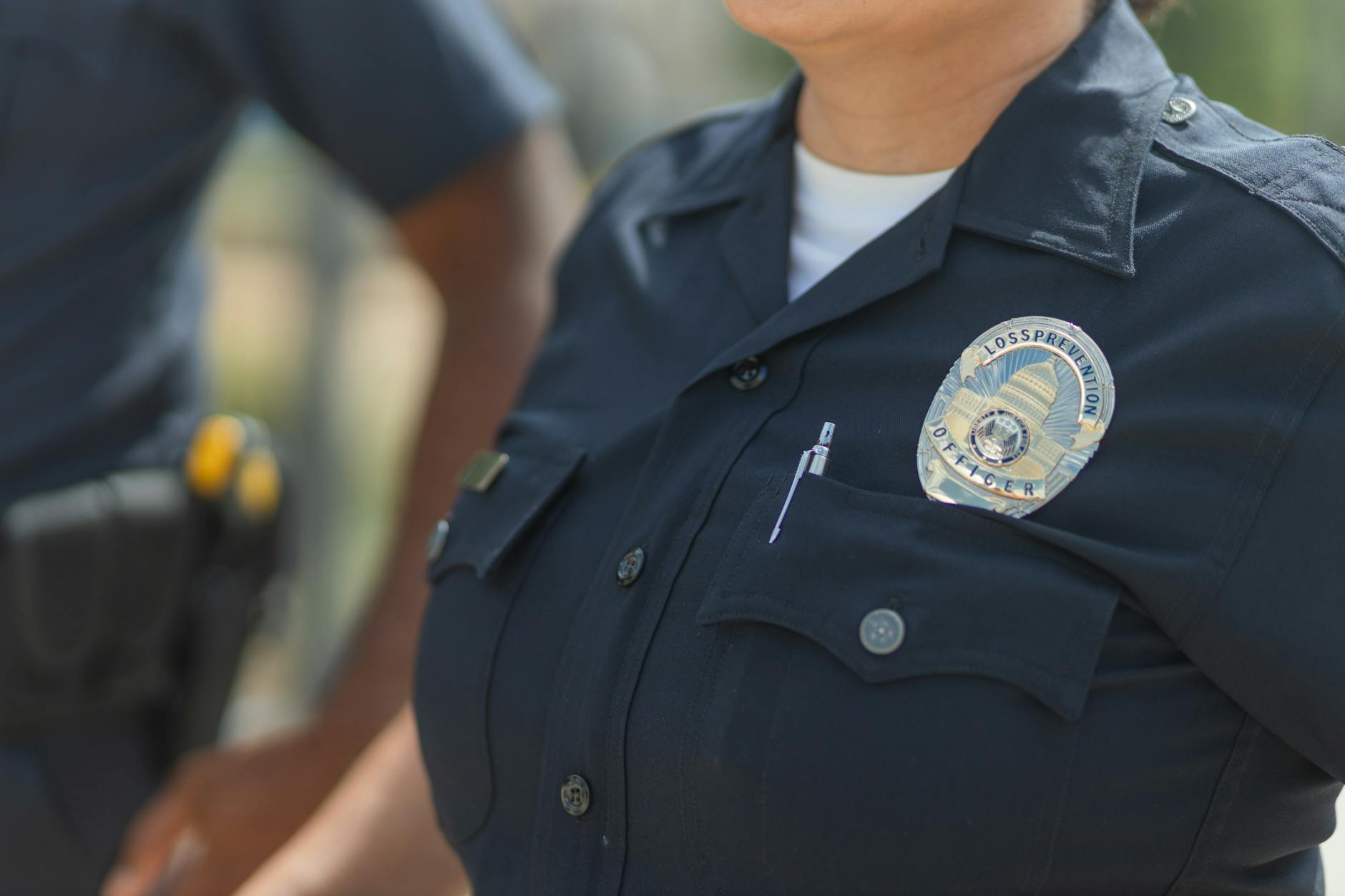 Close-up of police officers in uniform, displaying badge and radio outdoors — TransferCredit.org