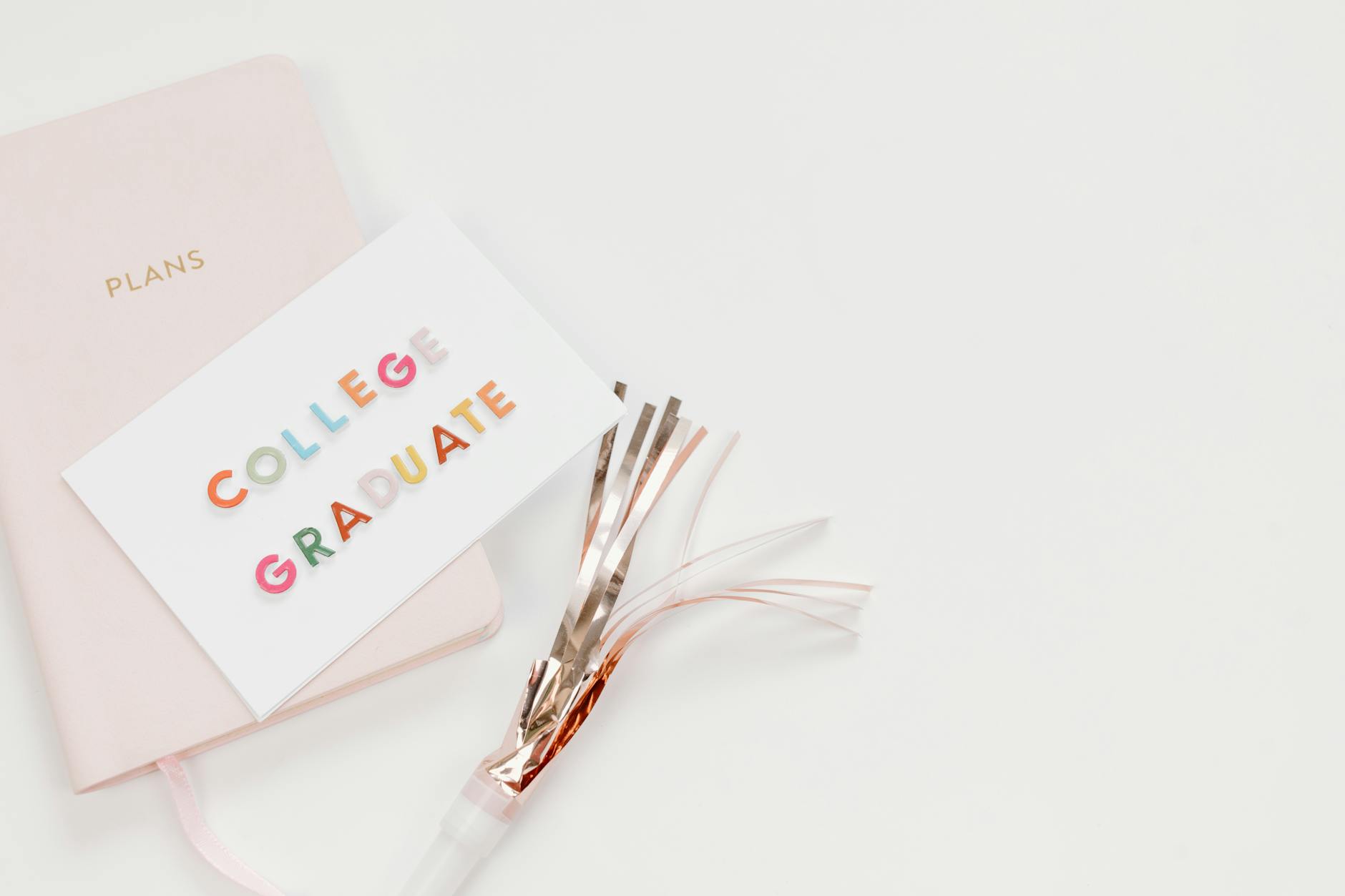 Elegant flat lay of a college graduate card with a notebook and party decor, perfect for celebration themes — TransferCredit.org