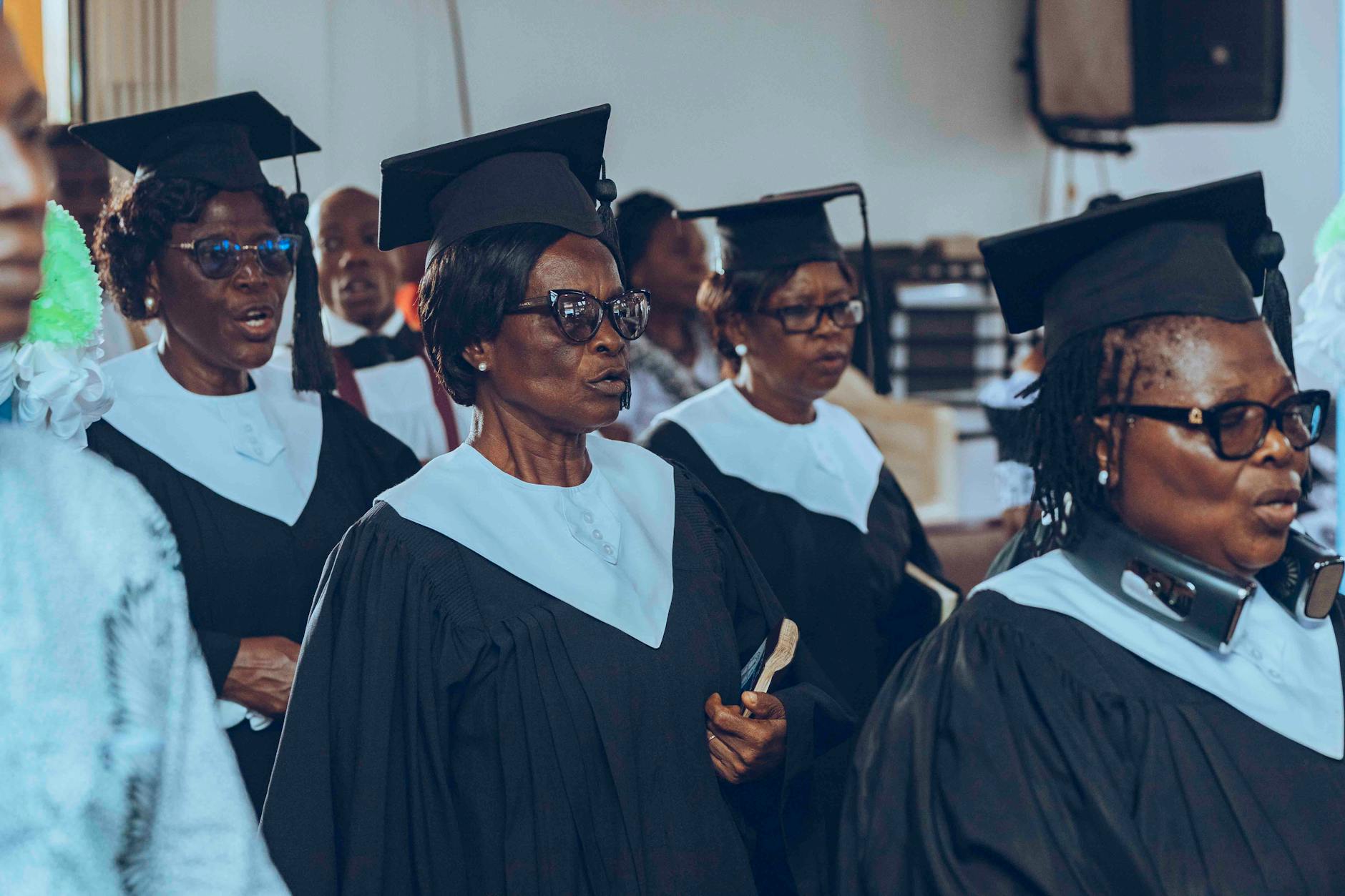 A group of senior adults wearing graduation caps and gowns at a ceremony — TransferCredit.org