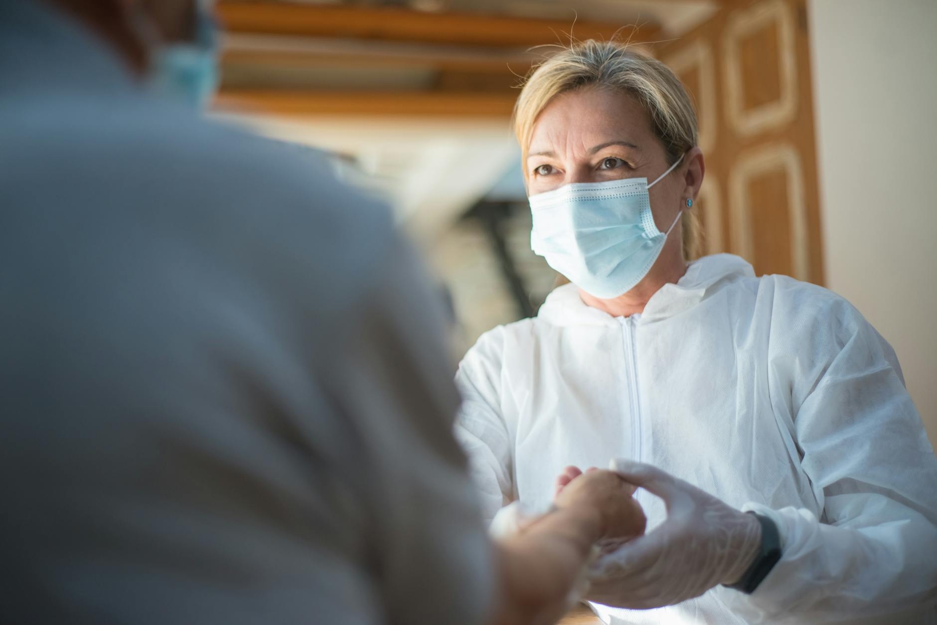A healthcare worker in protective gear providing care indoors. Focused face with surgical mask — TransferCredit.org
