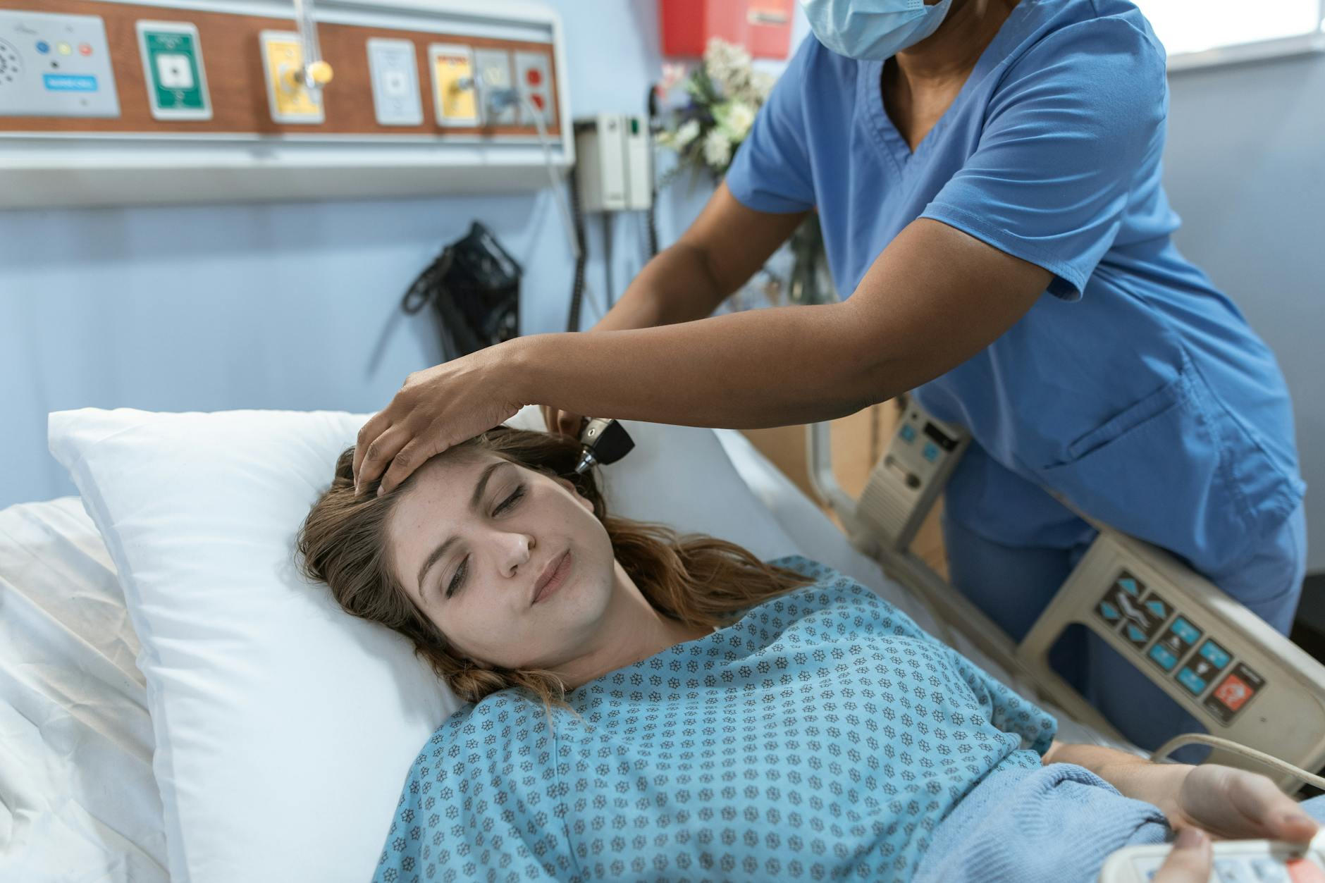 Crop African American female doctor with professional equipment doing examination of ear of woman lying on bed in hospital ward — TransferCredit.org