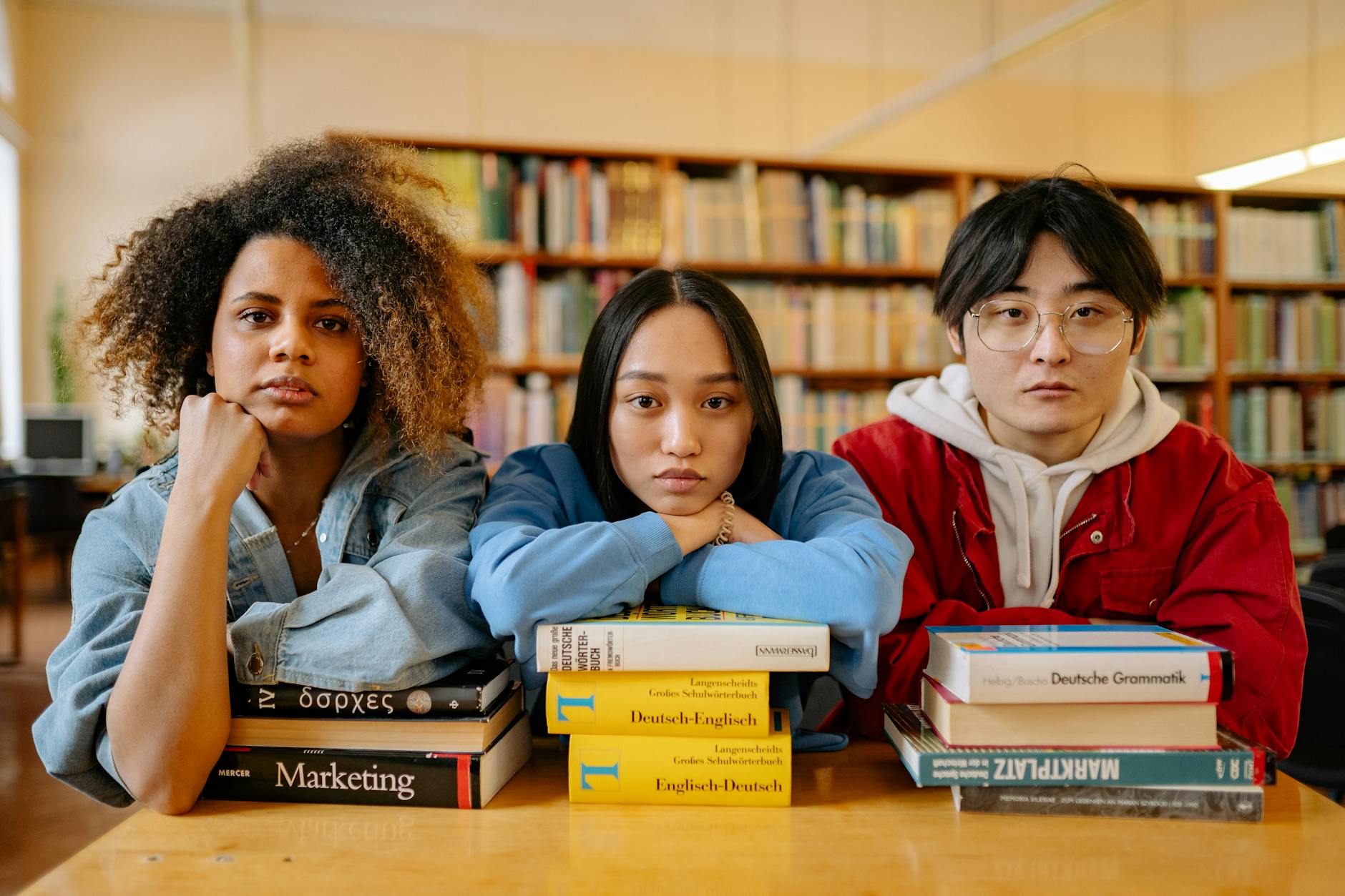 A group of diverse students engaging in studies at a library, surrounded by books and resources — TransferCredit.org