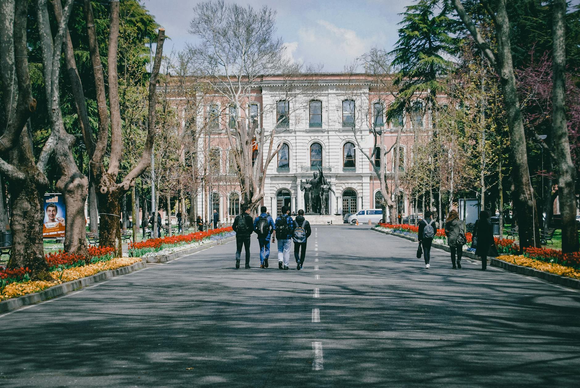 Students walking on a university campus surrounded by trees and spring flowers — TransferCredit.org
