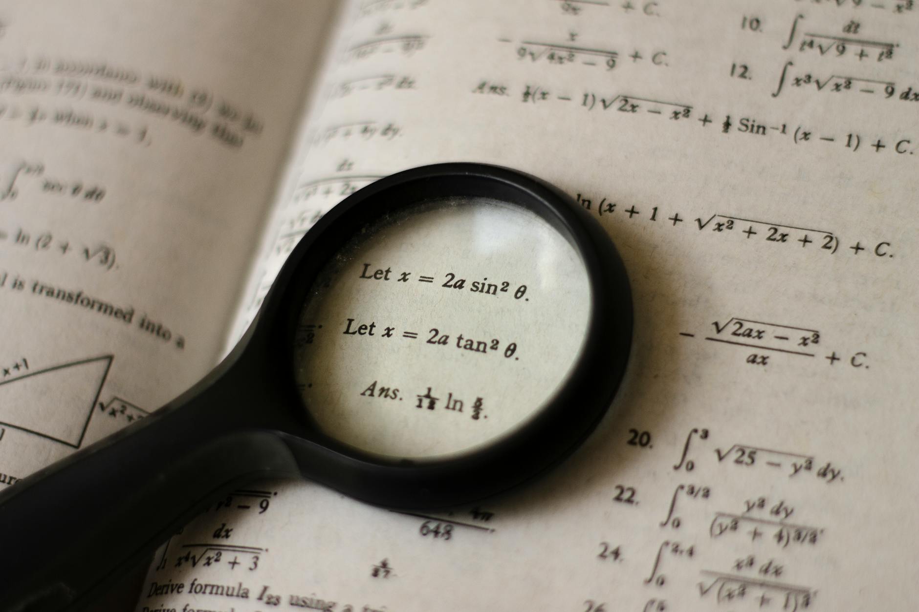 A magnifying glass focusing on mathematical equations in a textbook, symbolizing detailed study — TransferCredit.org