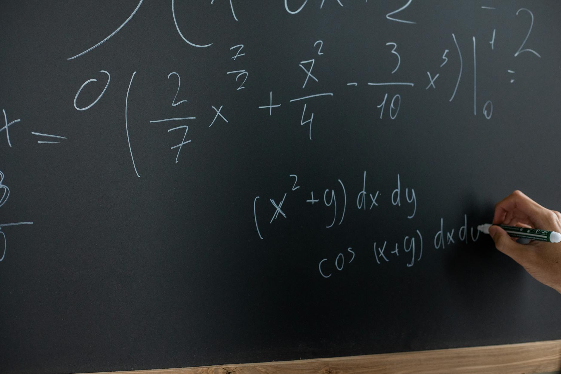 Hand writing mathematical equations on a chalkboard in a classroom setting — TransferCredit.org