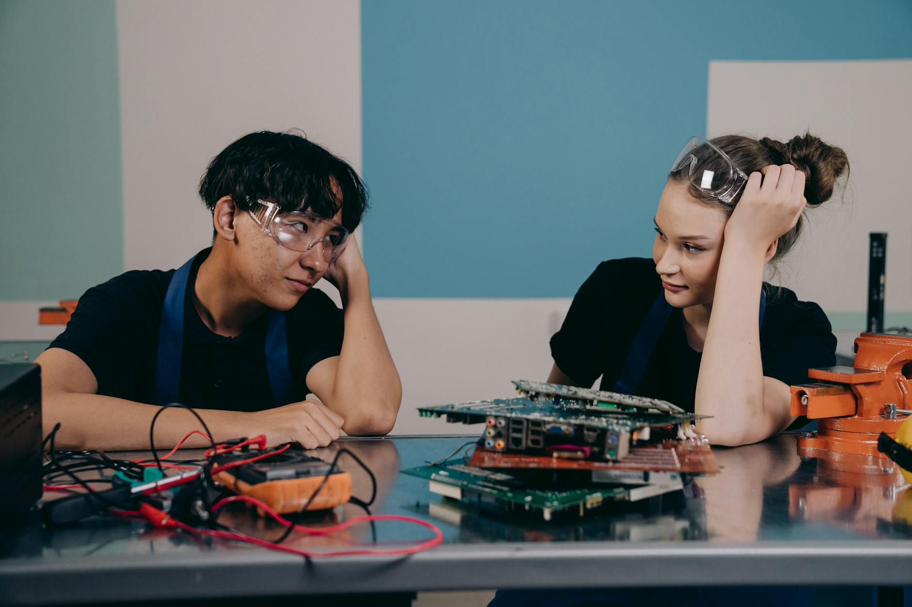 Two young engineers at a workbench, collaborating on electronics with circuit boards — TransferCredit.org
