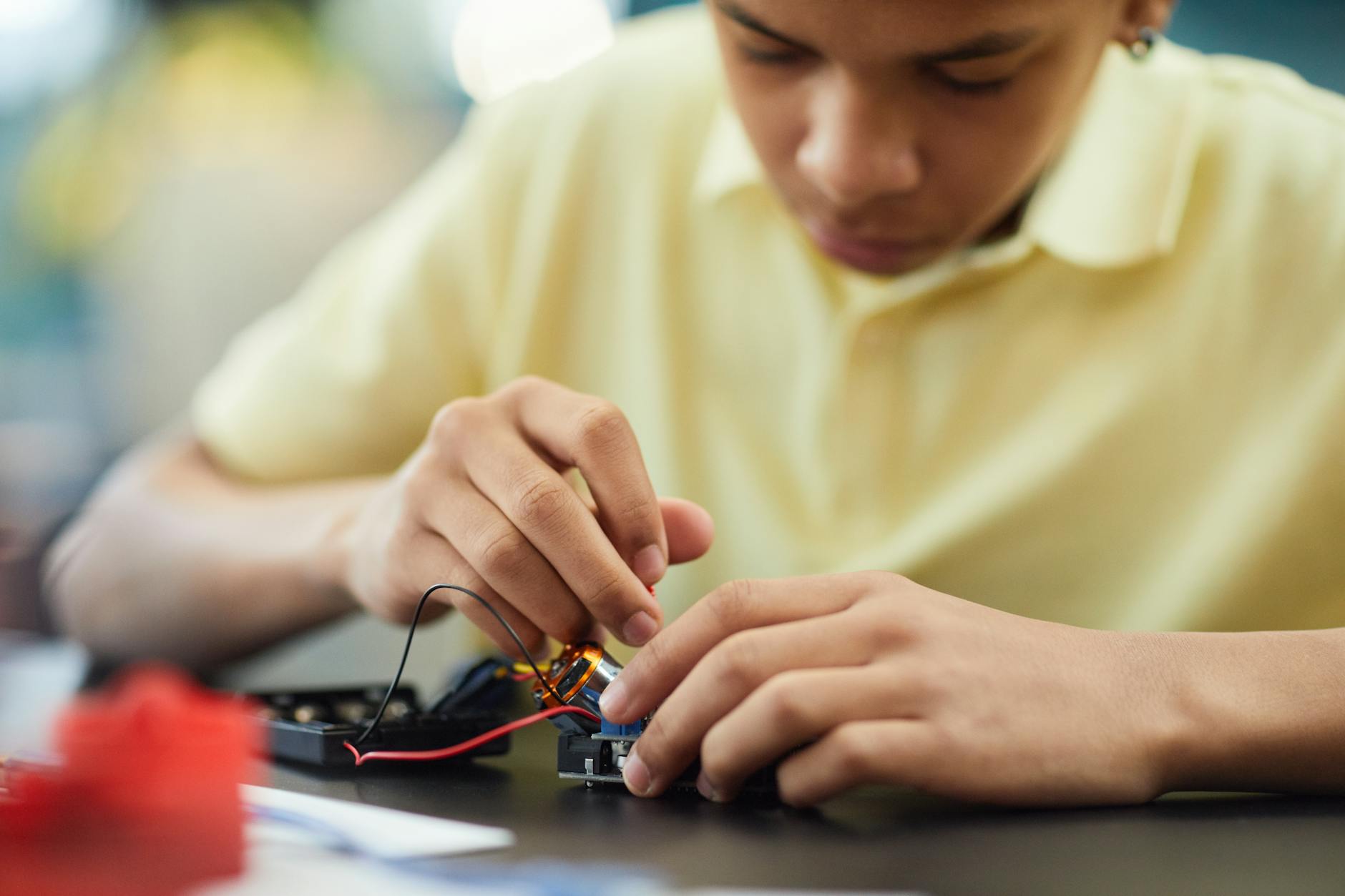 Close-up of a teenager building a robotics project, focusing on electronics and repairs — TransferCredit.org
