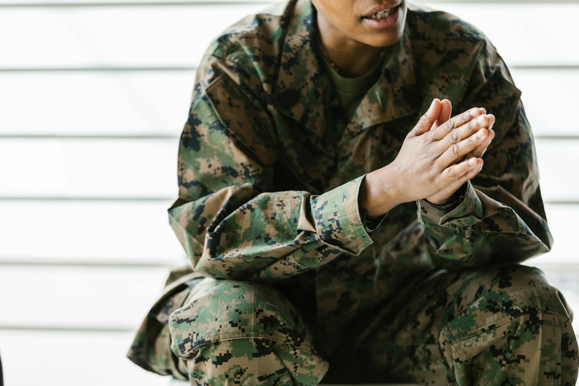 A close-up view of a soldier sitting in a camouflage uniform with clasped hands — TransferCredit.org
