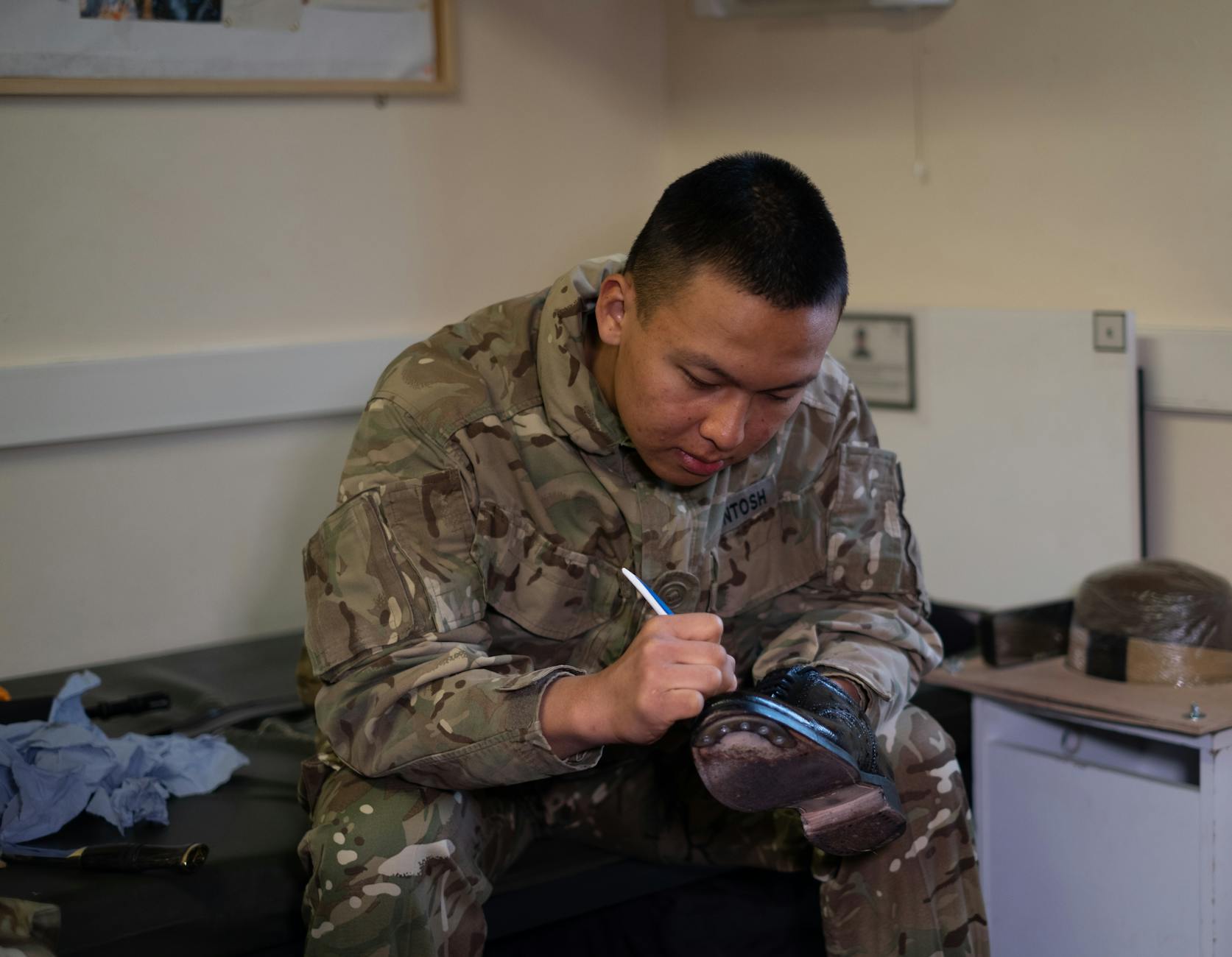 A British soldier is polishing boots indoors, showcasing military routine and discipline — TransferCredit.org