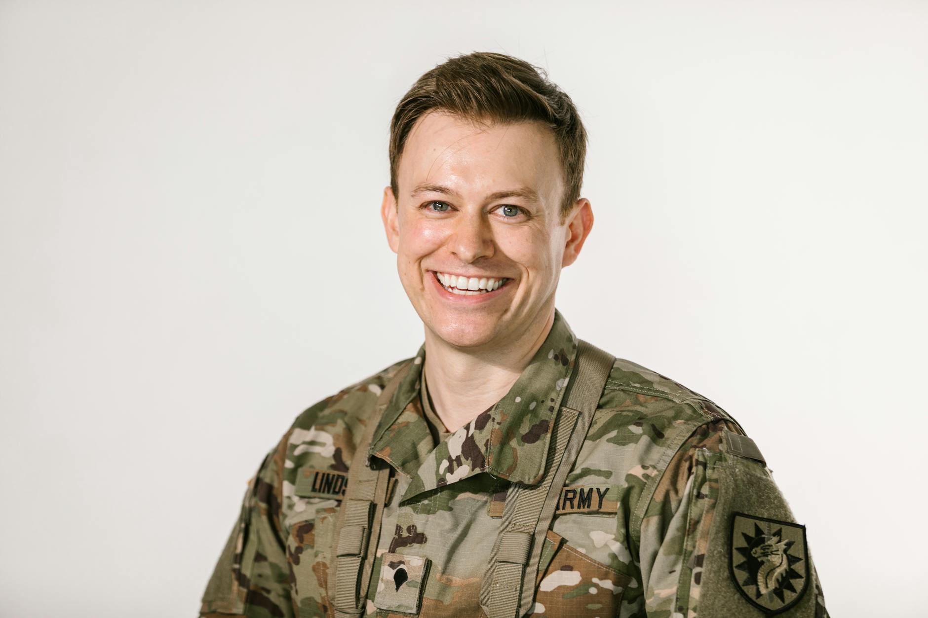 Portrait of a smiling US Army soldier in camouflage uniform on a white background — TransferCredit.org