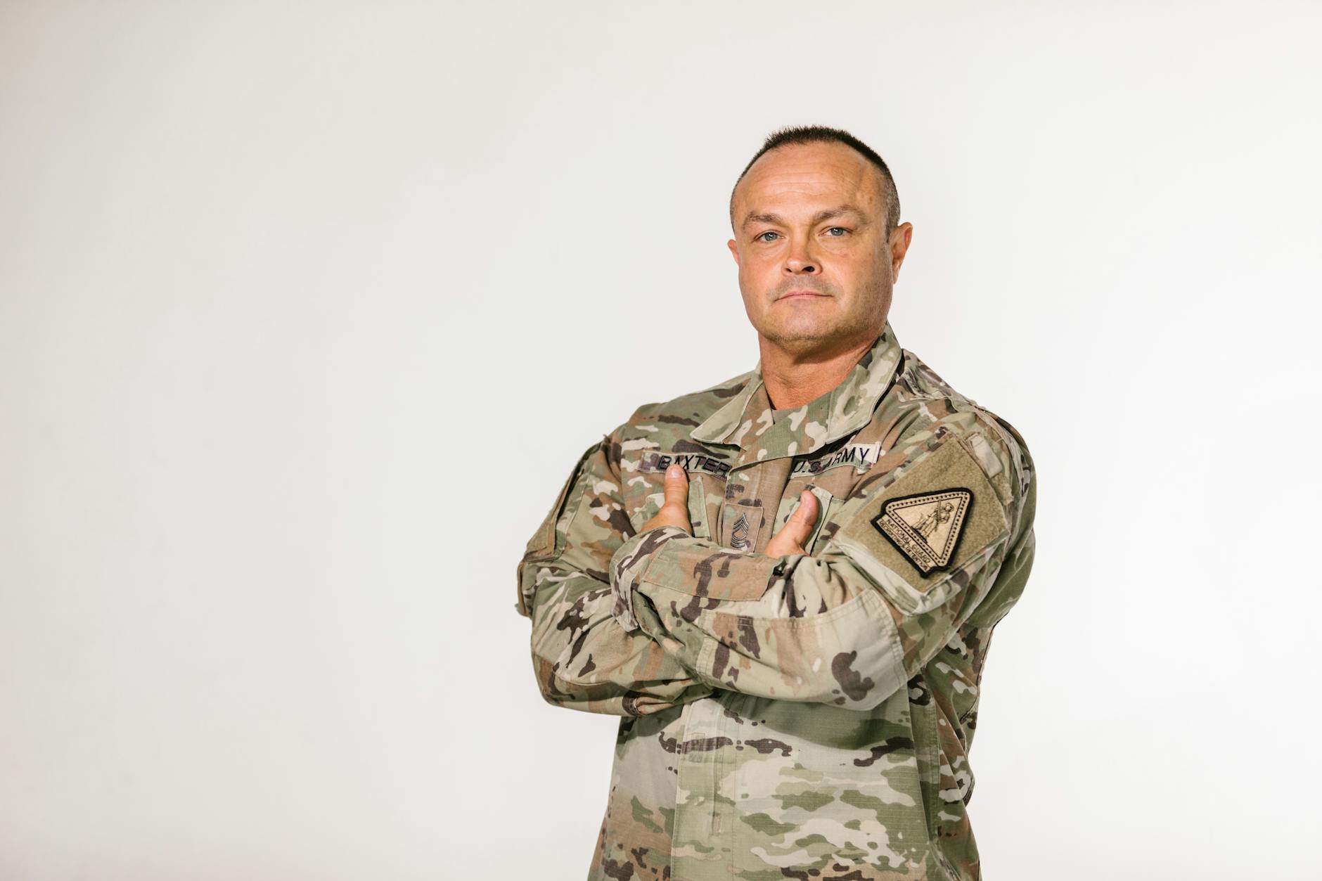 Military veteran standing with pride in camouflage uniform against a white background — TransferCredit.org