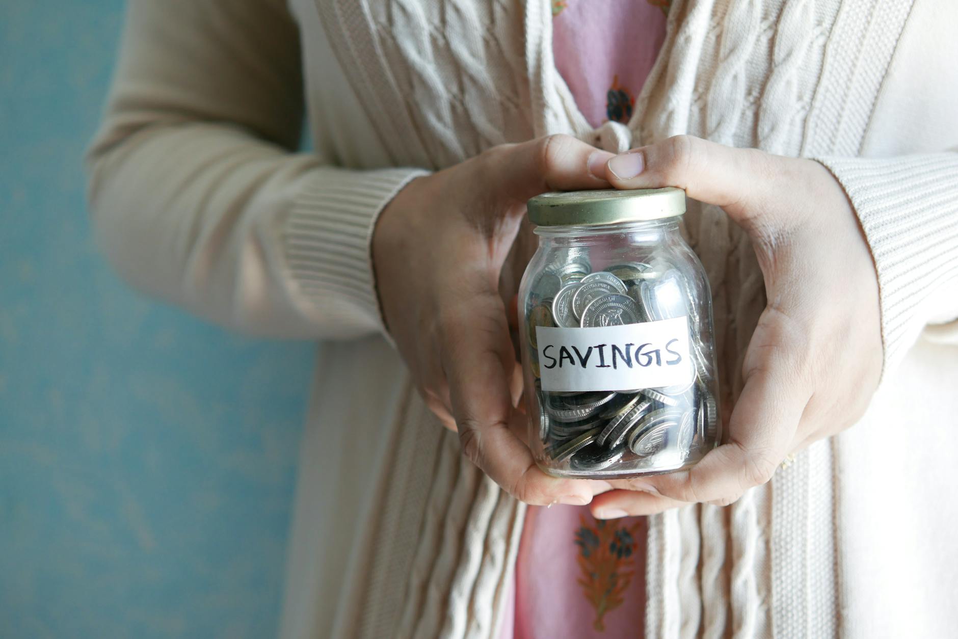 Woman holding a jar labeled 'savings' filled with coins, representing financial savings — TransferCredit.org