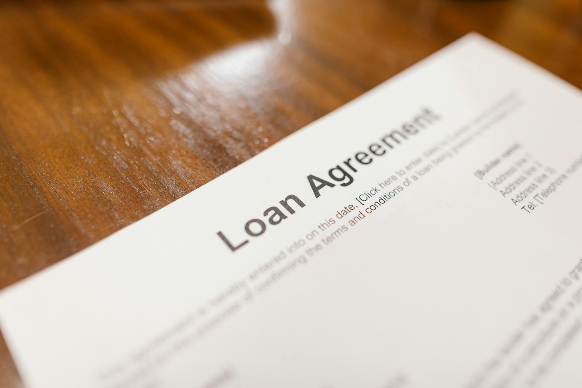 Detailed loan agreement document close-up on a wooden table representing legal and financial concepts — TransferCredit.org