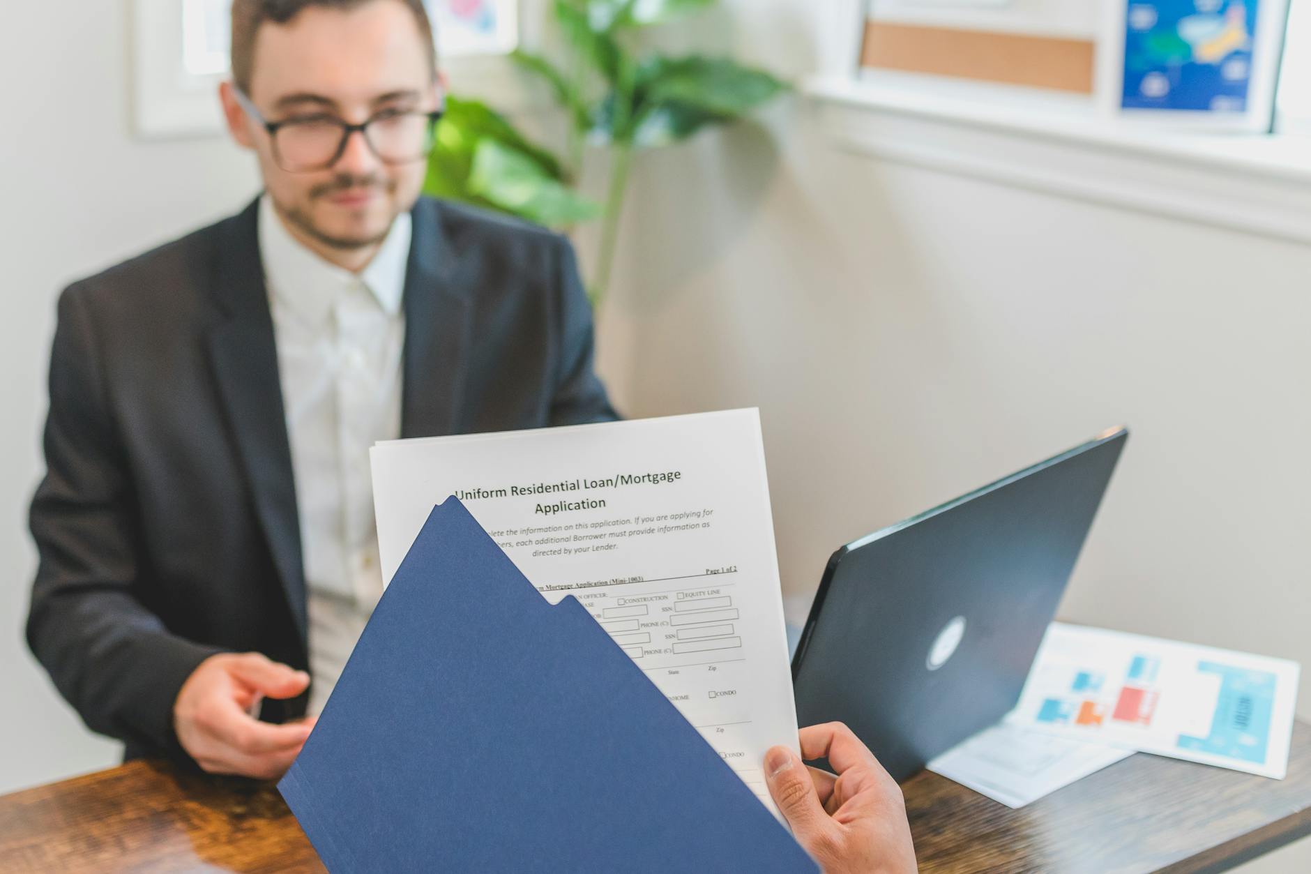 Mortgage broker and client discussing loan application with documents on table — TransferCredit.org