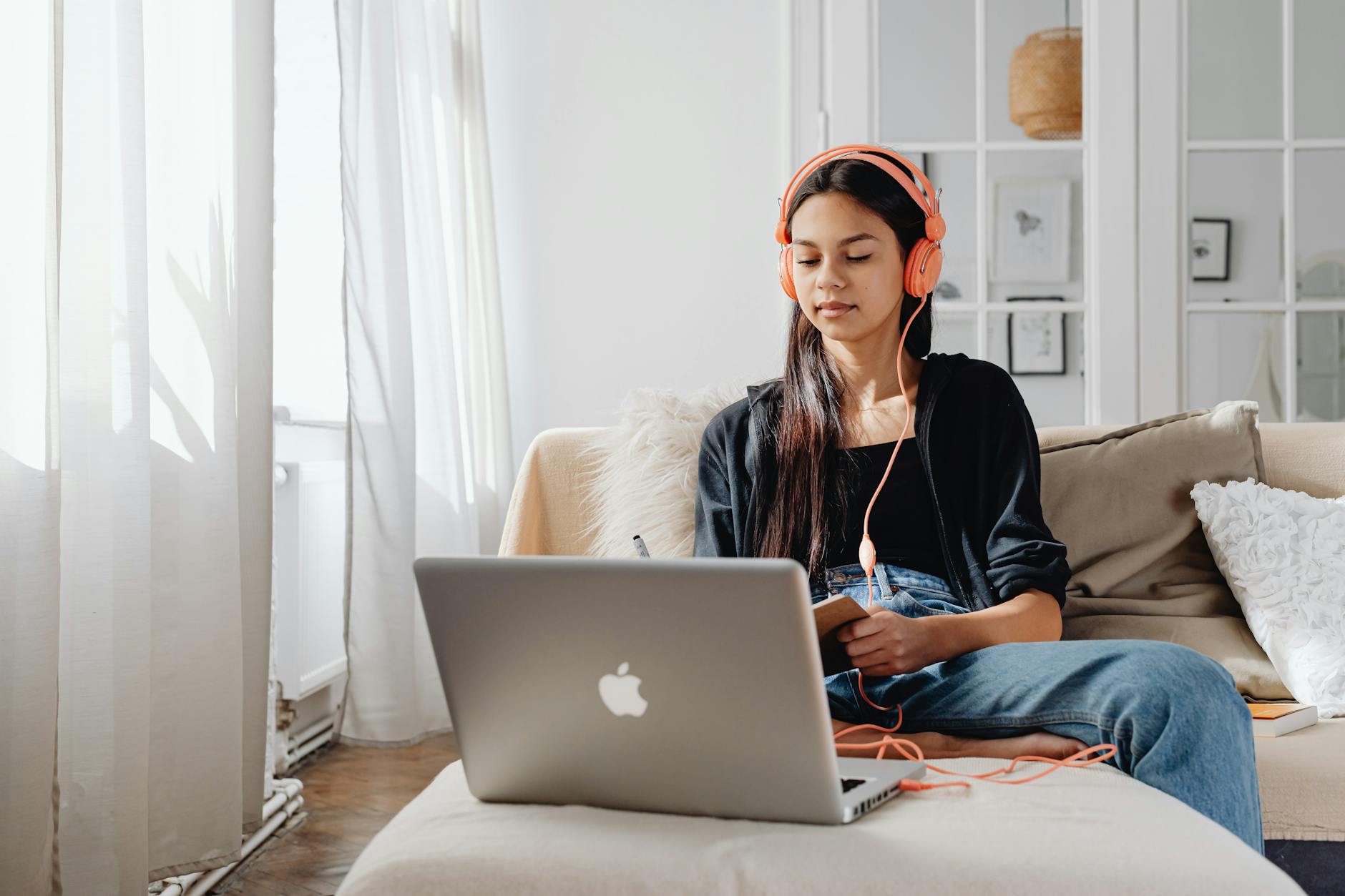 Teenage girl wearing headphones using a laptop for online learning at home in a cozy setting — TransferCredit.org