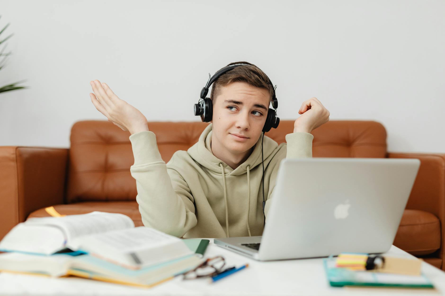 Young man in hoodie using laptop and headphones for online learning at home — TransferCredit.org