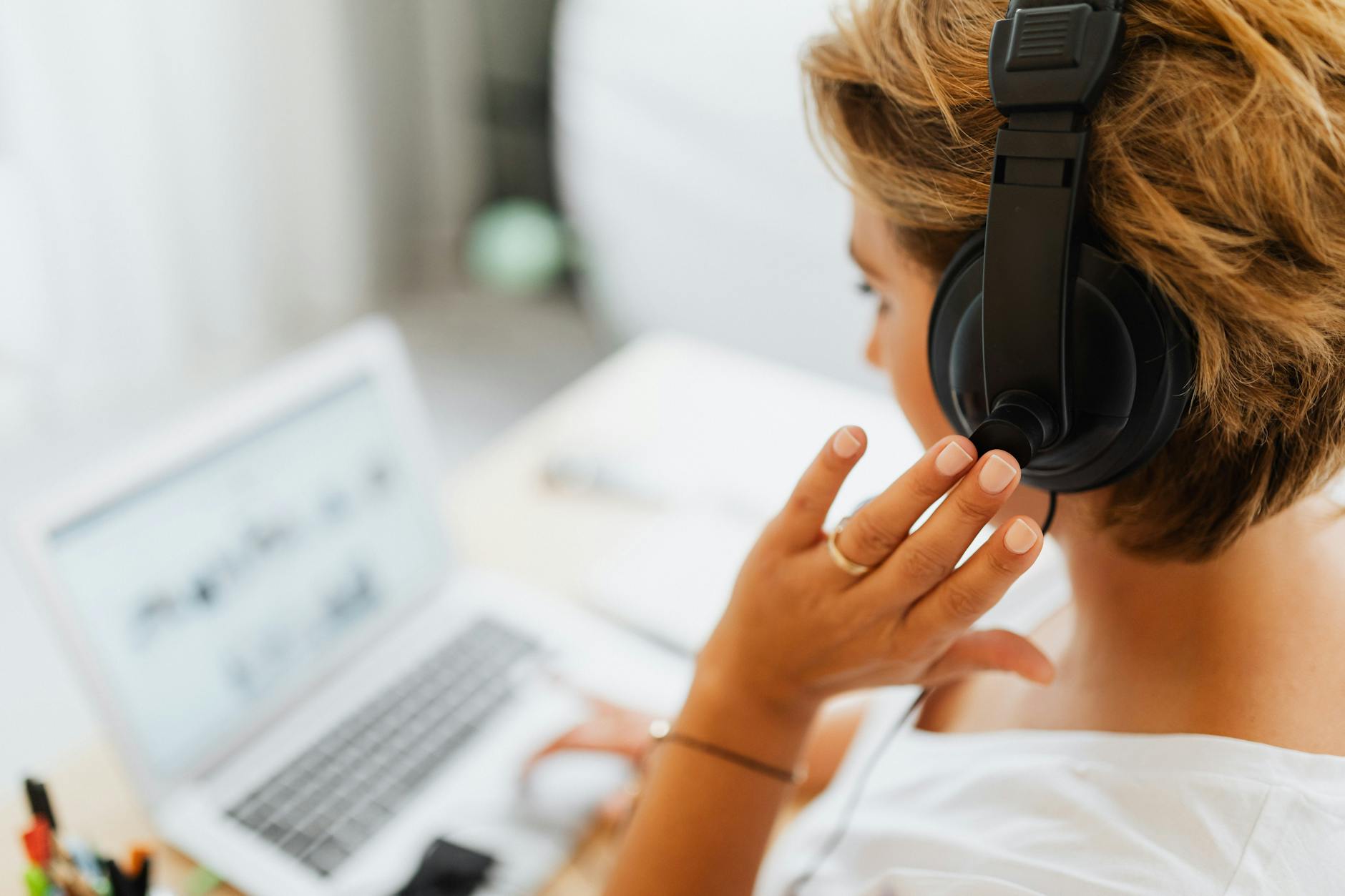 Woman at home using headphones and laptop for online work or video call — TransferCredit.org