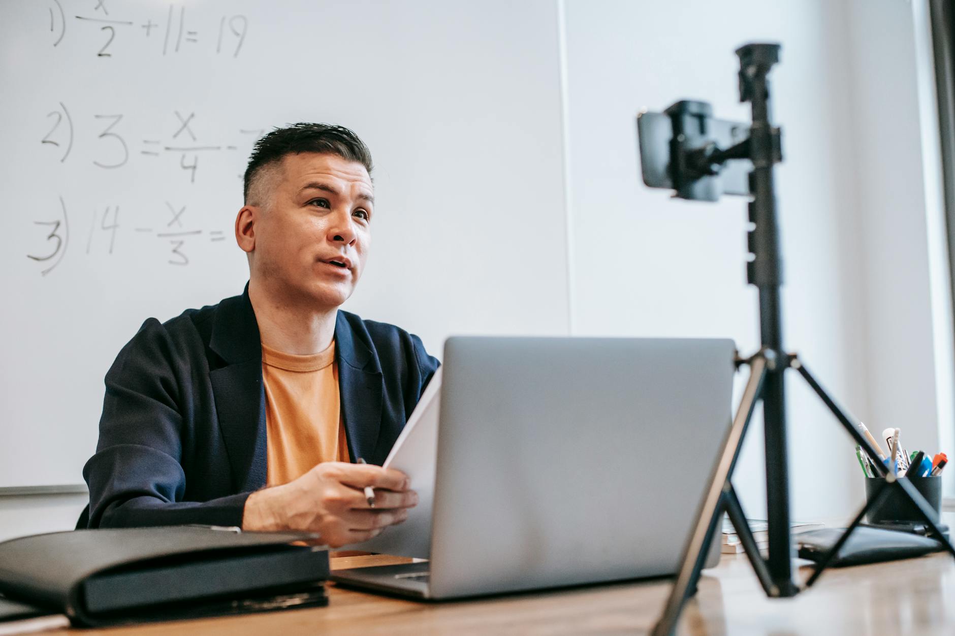 Male instructor conducting an online education session with a laptop and camera — TransferCredit.org