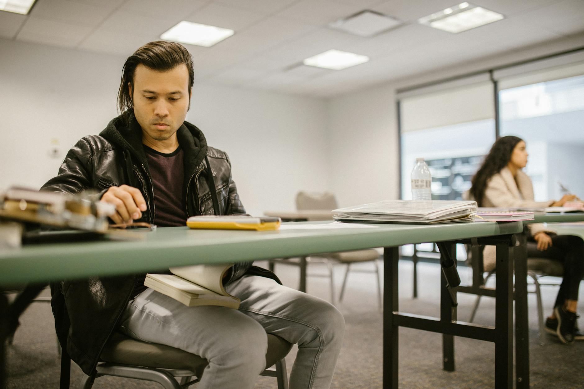Two college students engaged in focused study at a classroom desk, preparing for exams — TransferCredit.org