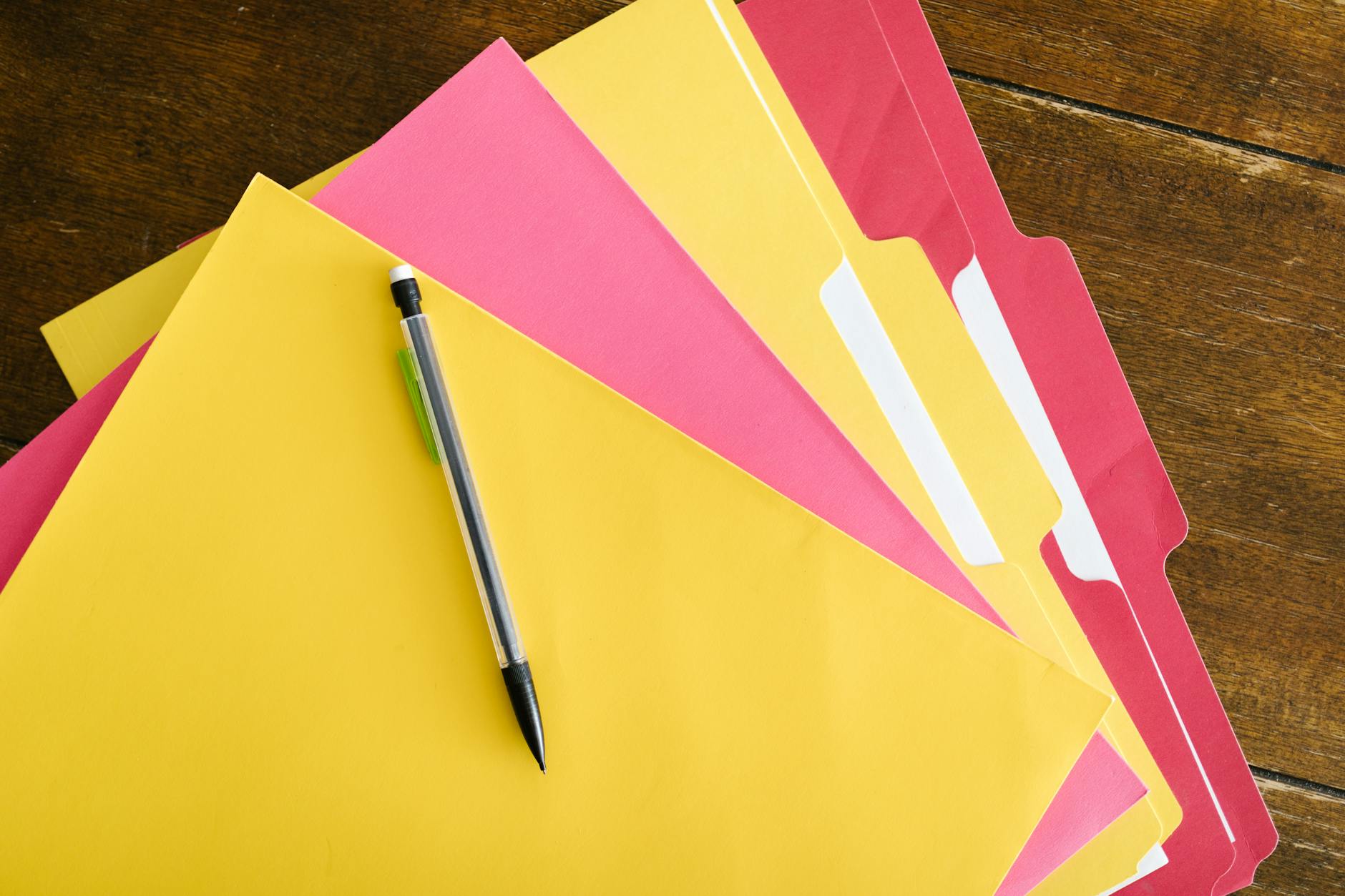 Colorful folders and pen arranged on a wooden table for office organization — TransferCredit.org