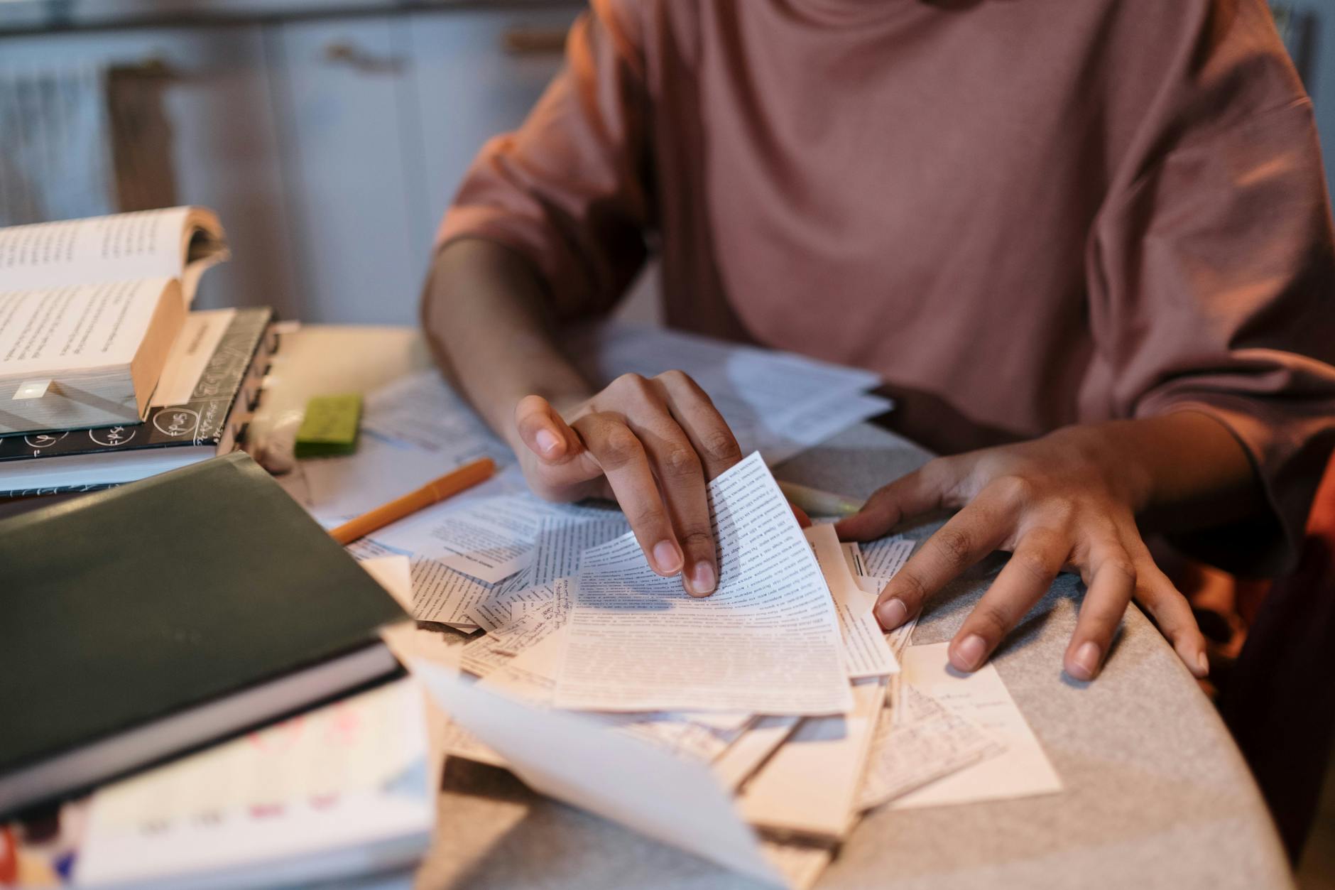 A young woman intensely studying with textbooks and notes scattered on a table — TransferCredit.org