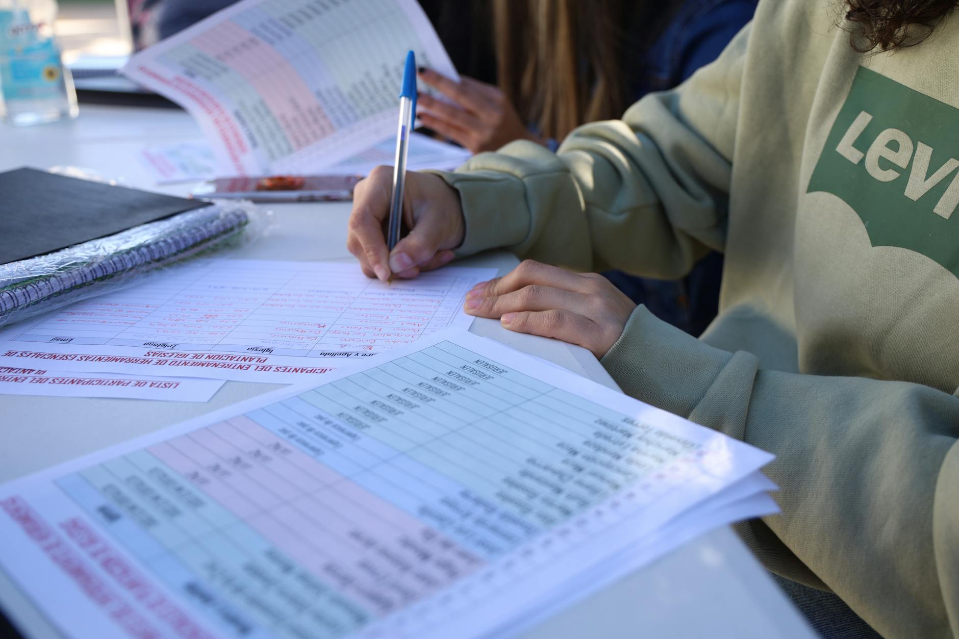 Person writing on documents outdoors, focusing on planning and organization — TransferCredit.org