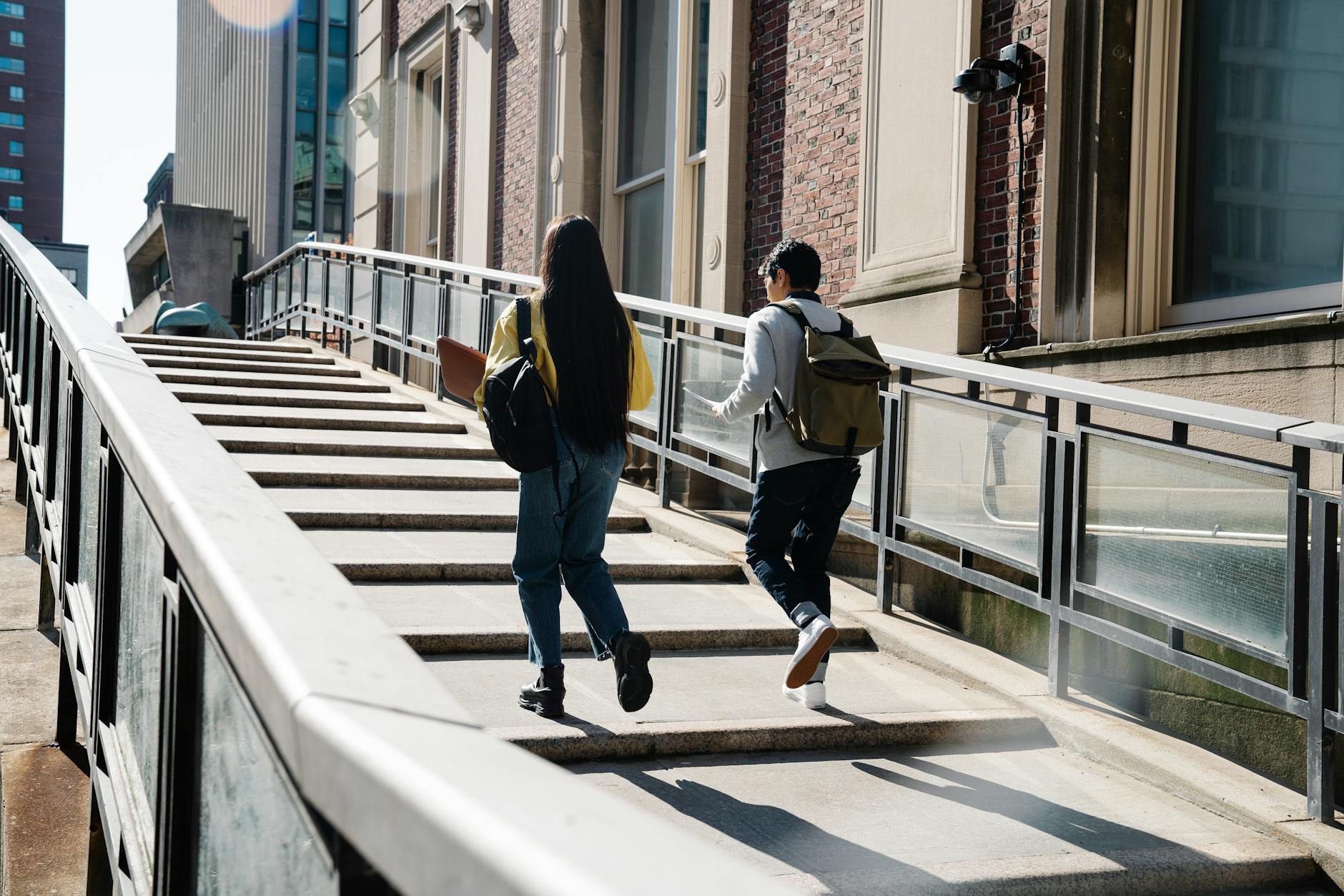 Two students walk up an outdoor staircase toward a university building — TransferCredit.org