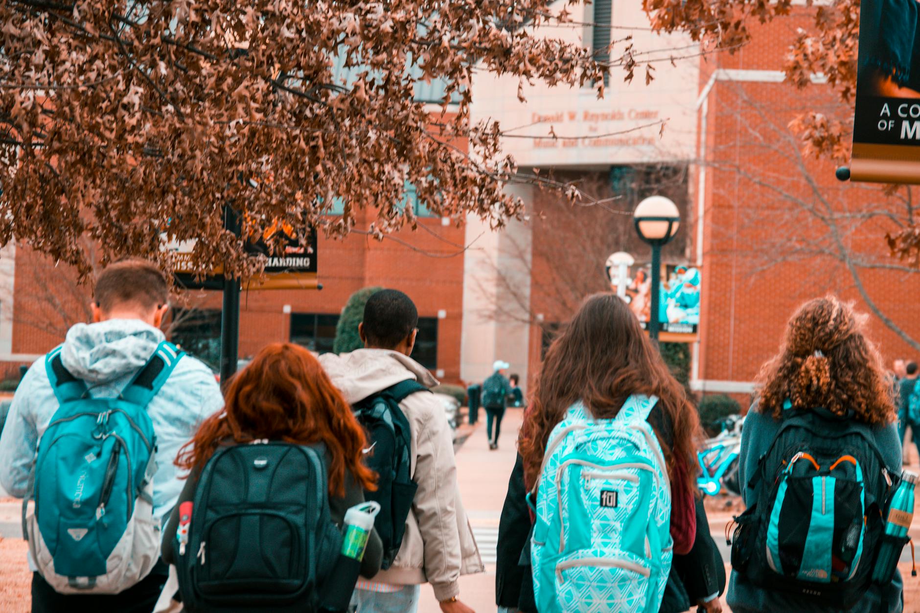 A group of college students with backpacks walking together outdoors on campus — TransferCredit.org