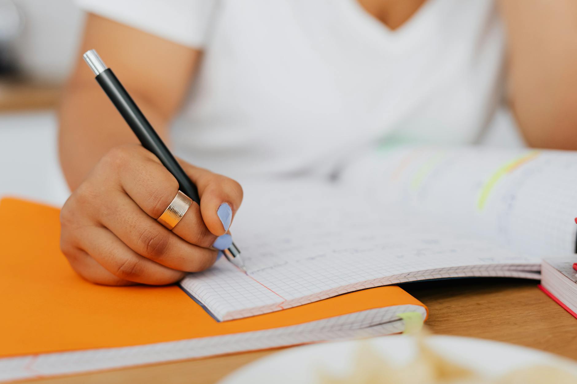 Detailed shot of a woman's hand writing in a notebook, ideal for education-themed content — TransferCredit.org